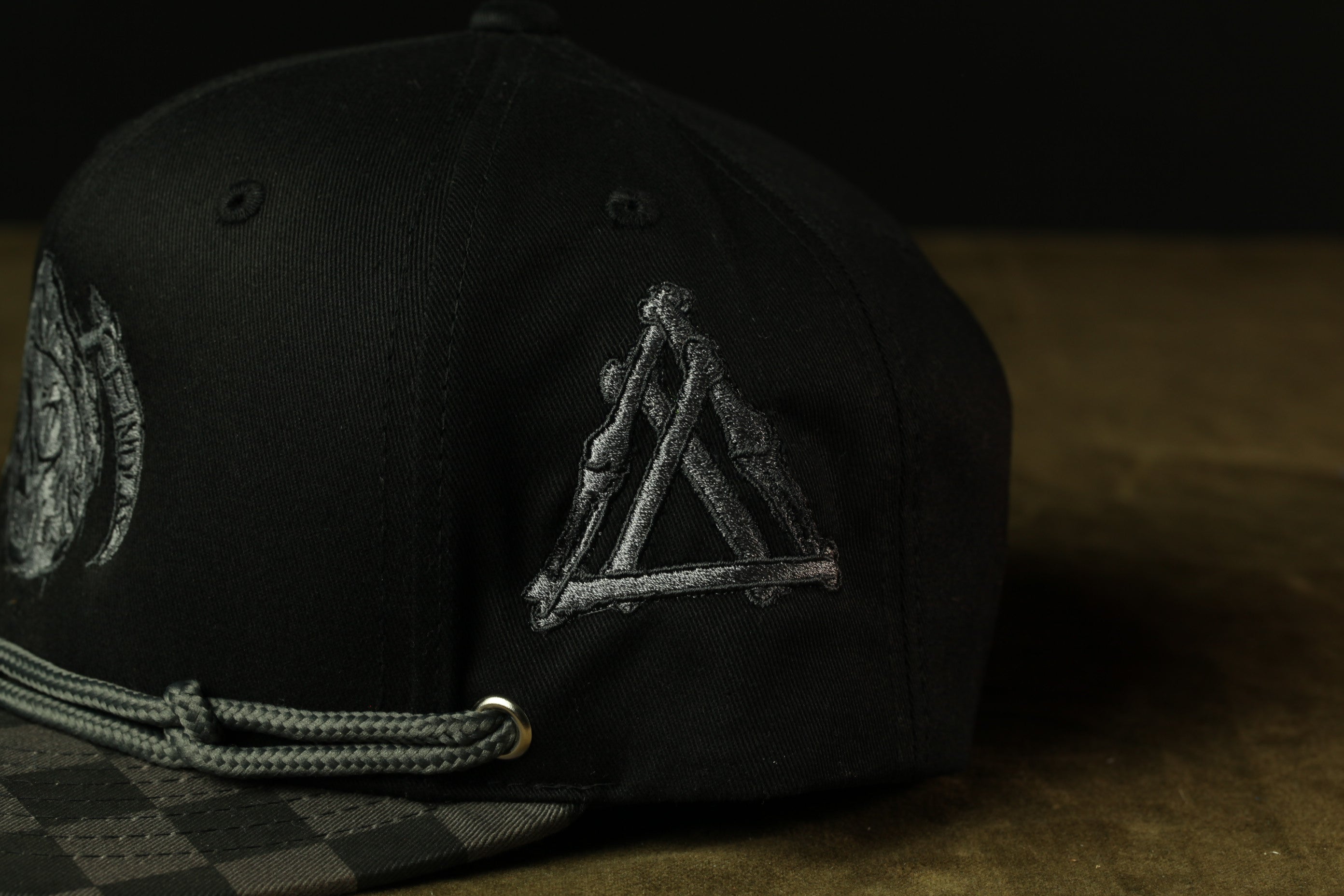 A close-up view of a black baseball cap with a distinctive triangle-shaped logo on the side.