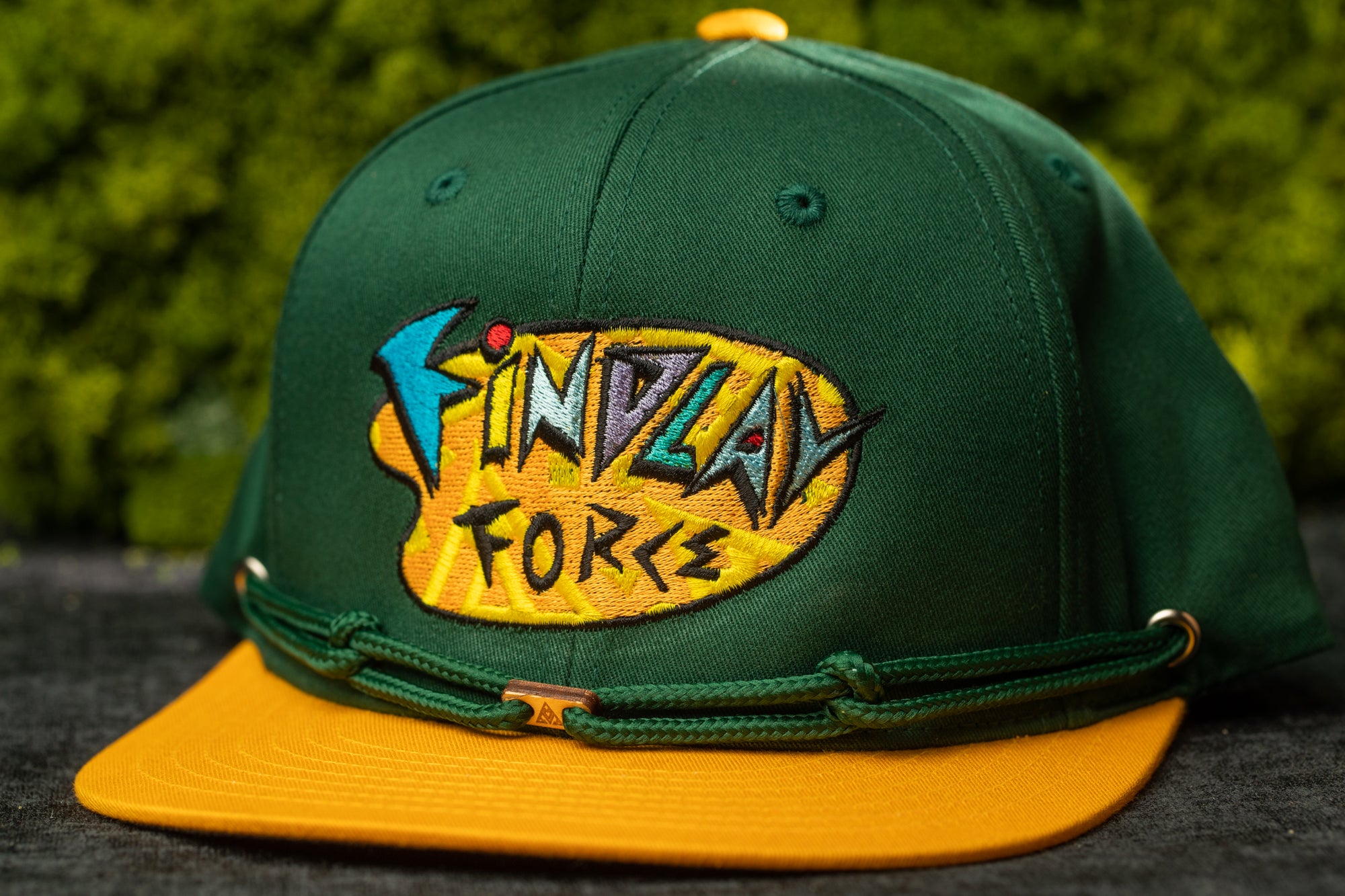 A green baseball cap with a yellow brim and a colorful logo on the front.