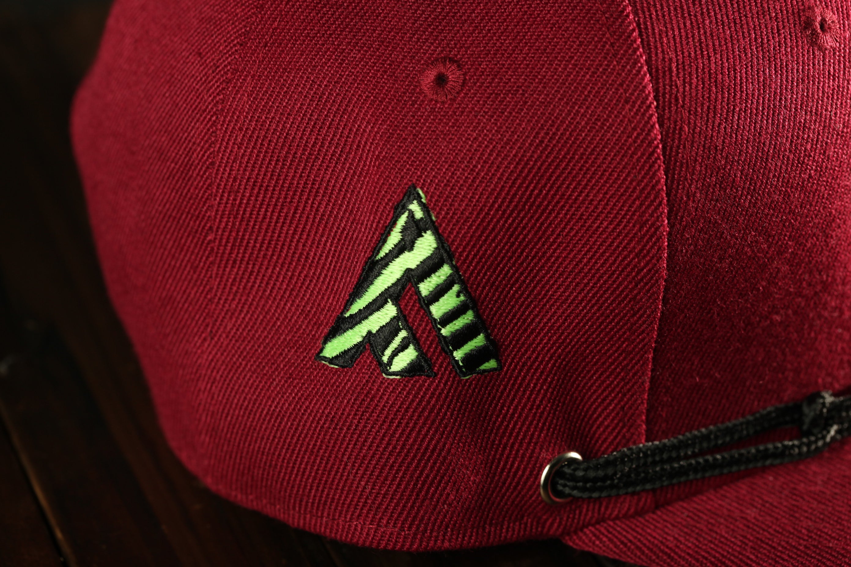 A close-up view of a red baseball cap with a green and black zebra-striped logo on the front.