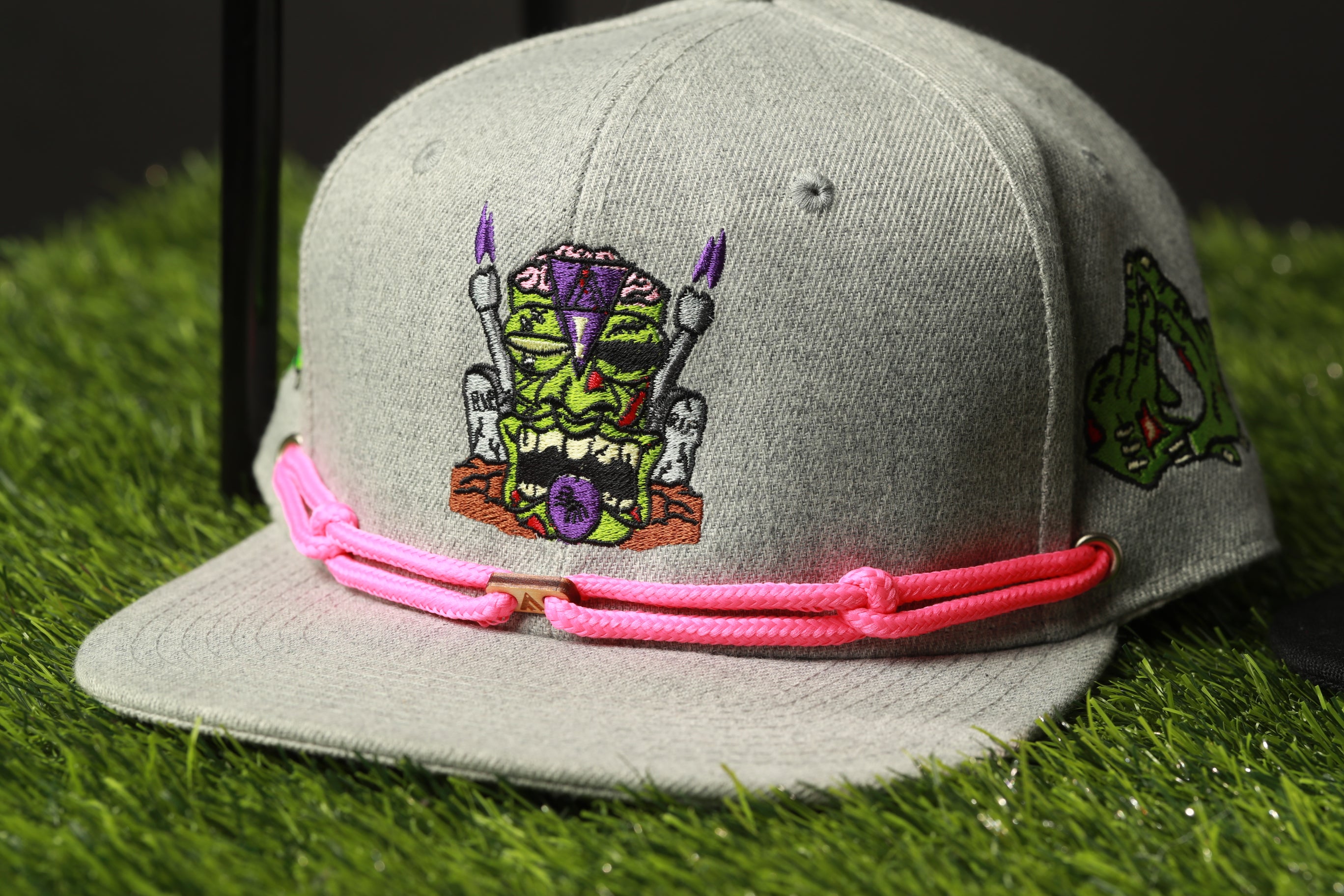 A gray baseball cap with a colorful, cartoonish design on the front, featuring a character with a skull and crossbones motif.