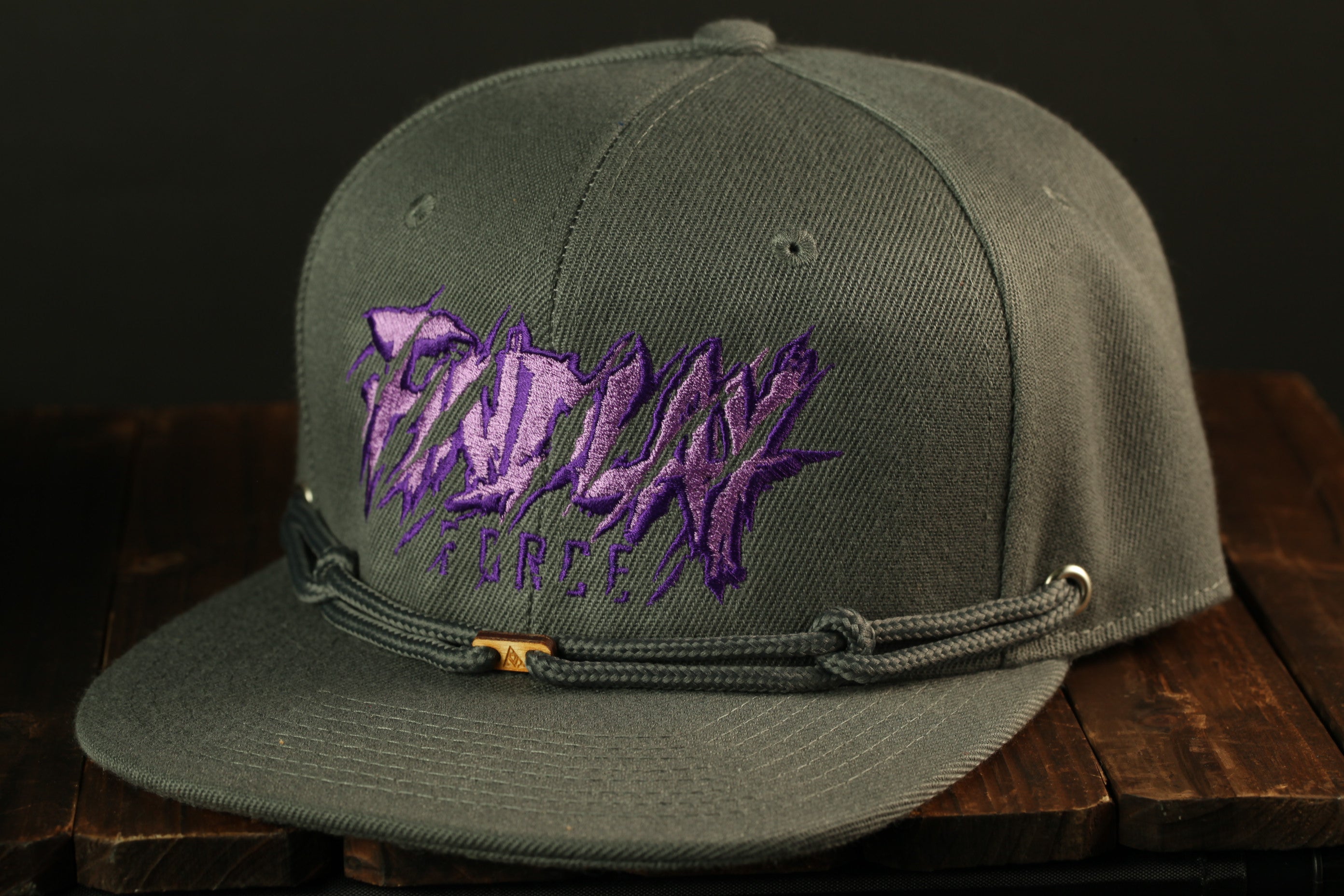 A gray baseball cap with purple text and a metal buckle on the front.