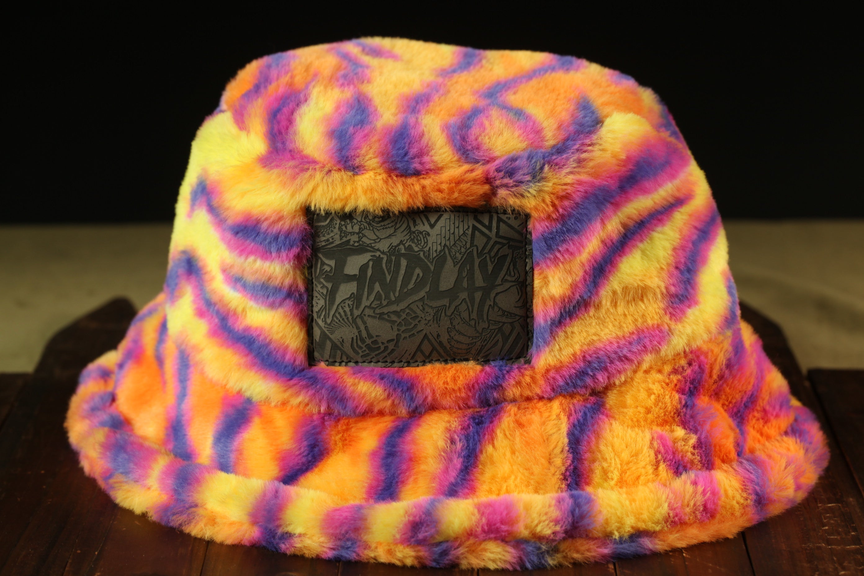 A colorful, multicolored bucket hat with a black patch on the front displaying the text "FINDLAY".