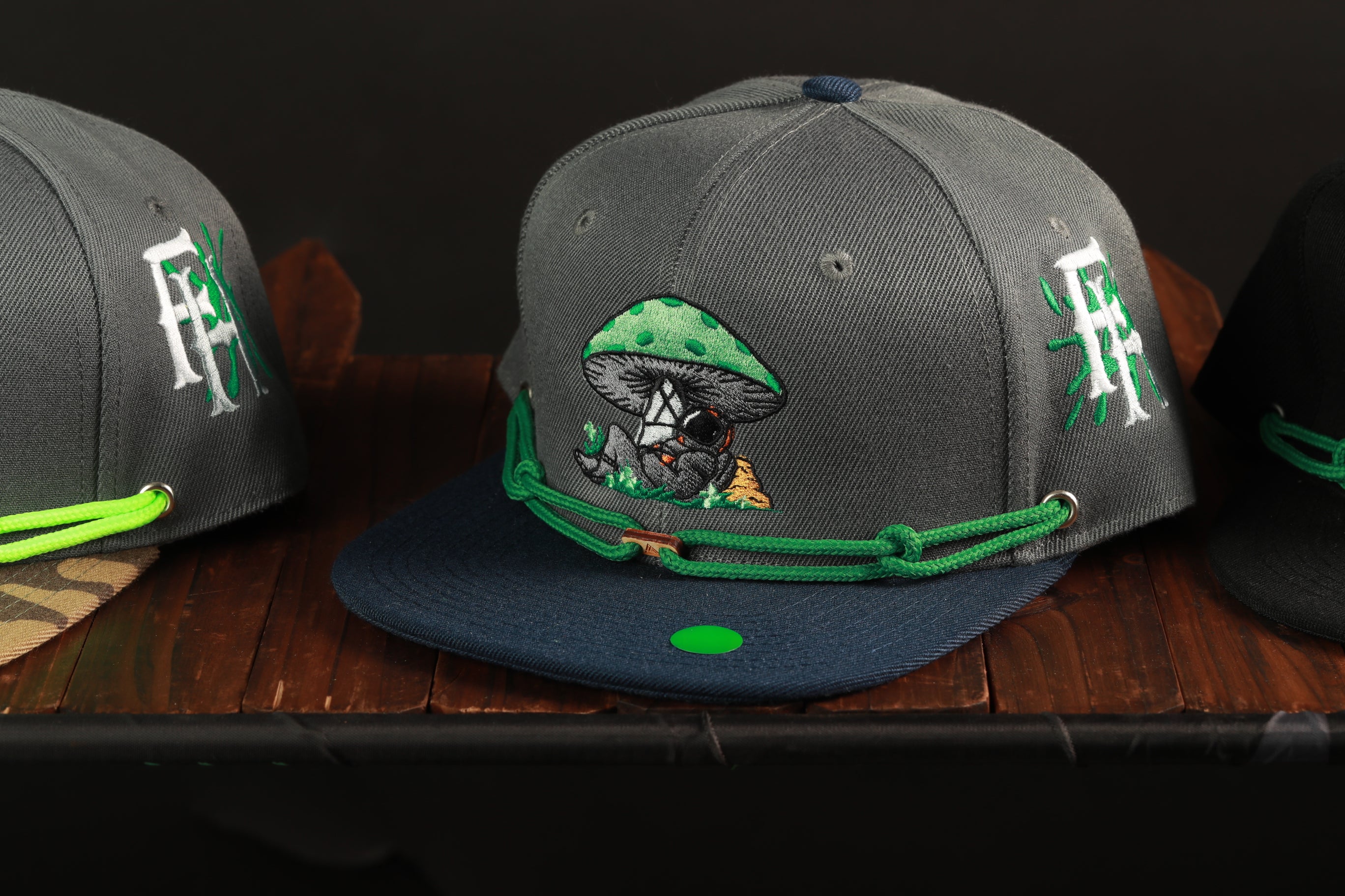 A gray baseball cap with a green and white mushroom design, featuring a small green dot on the front.