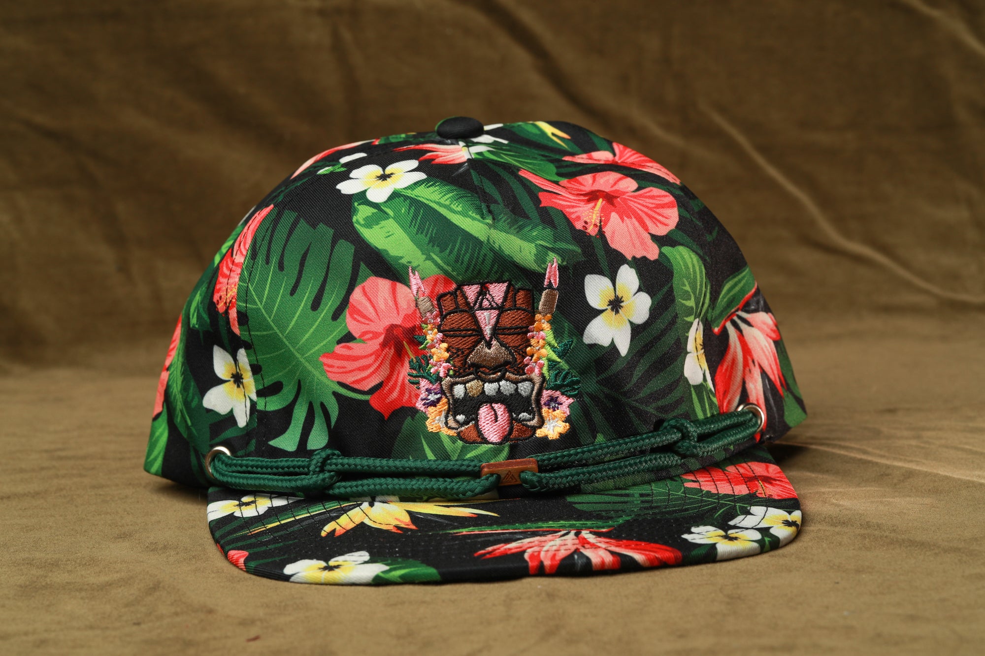 A colorful floral printed baseball cap with a tiki mask design on the front.