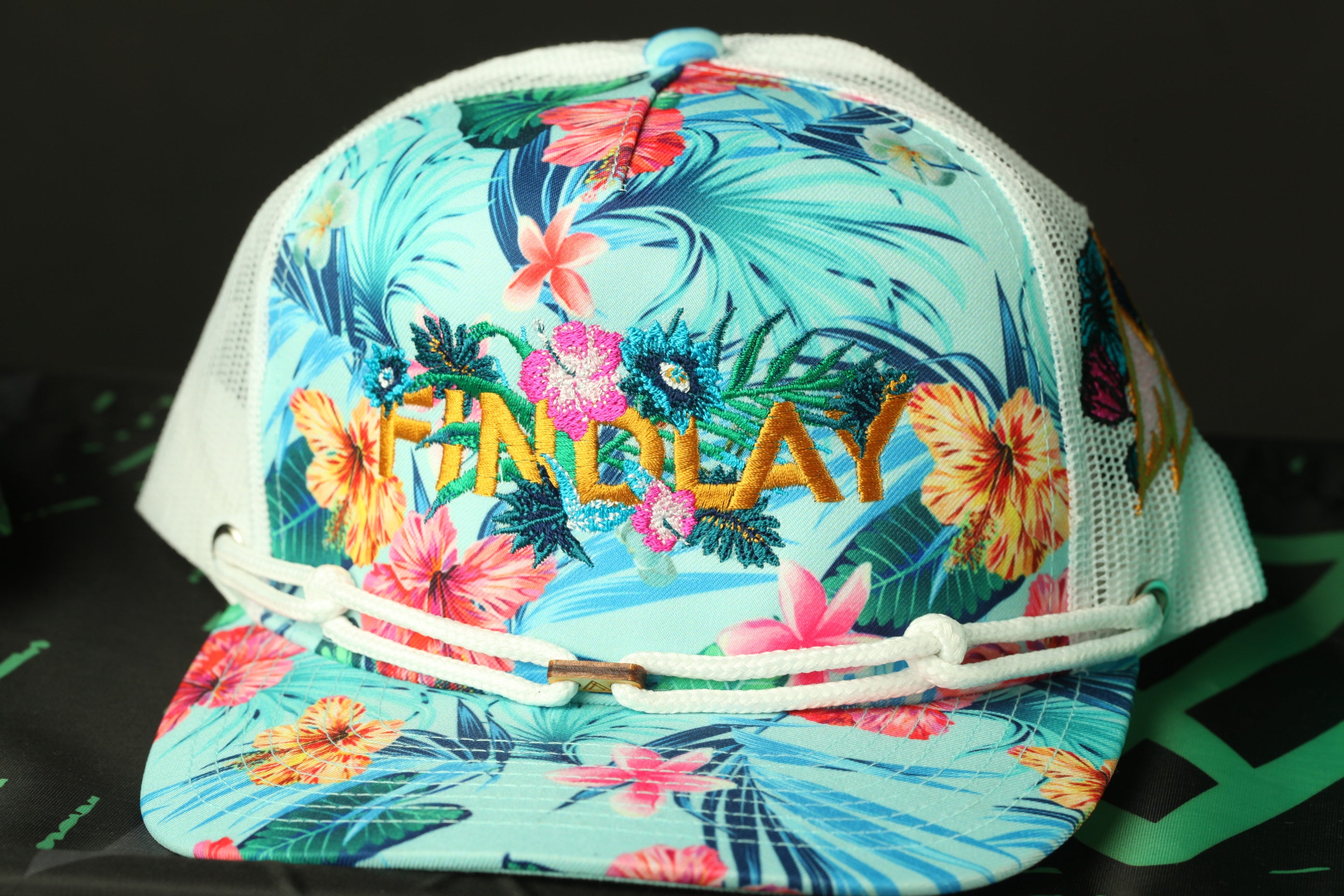 A colorful floral printed baseball cap with the word "FINDA" embroidered on it.