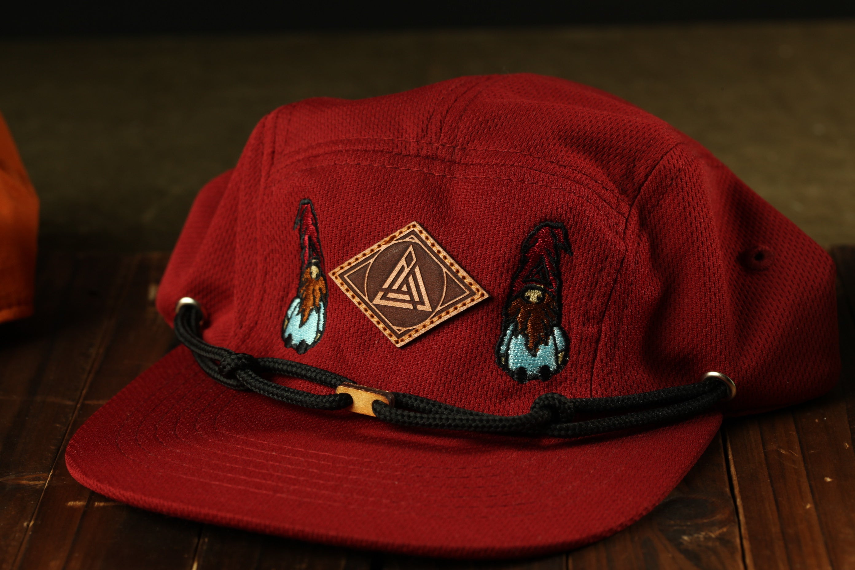 A red baseball cap with a black band and embroidered designs on the front.