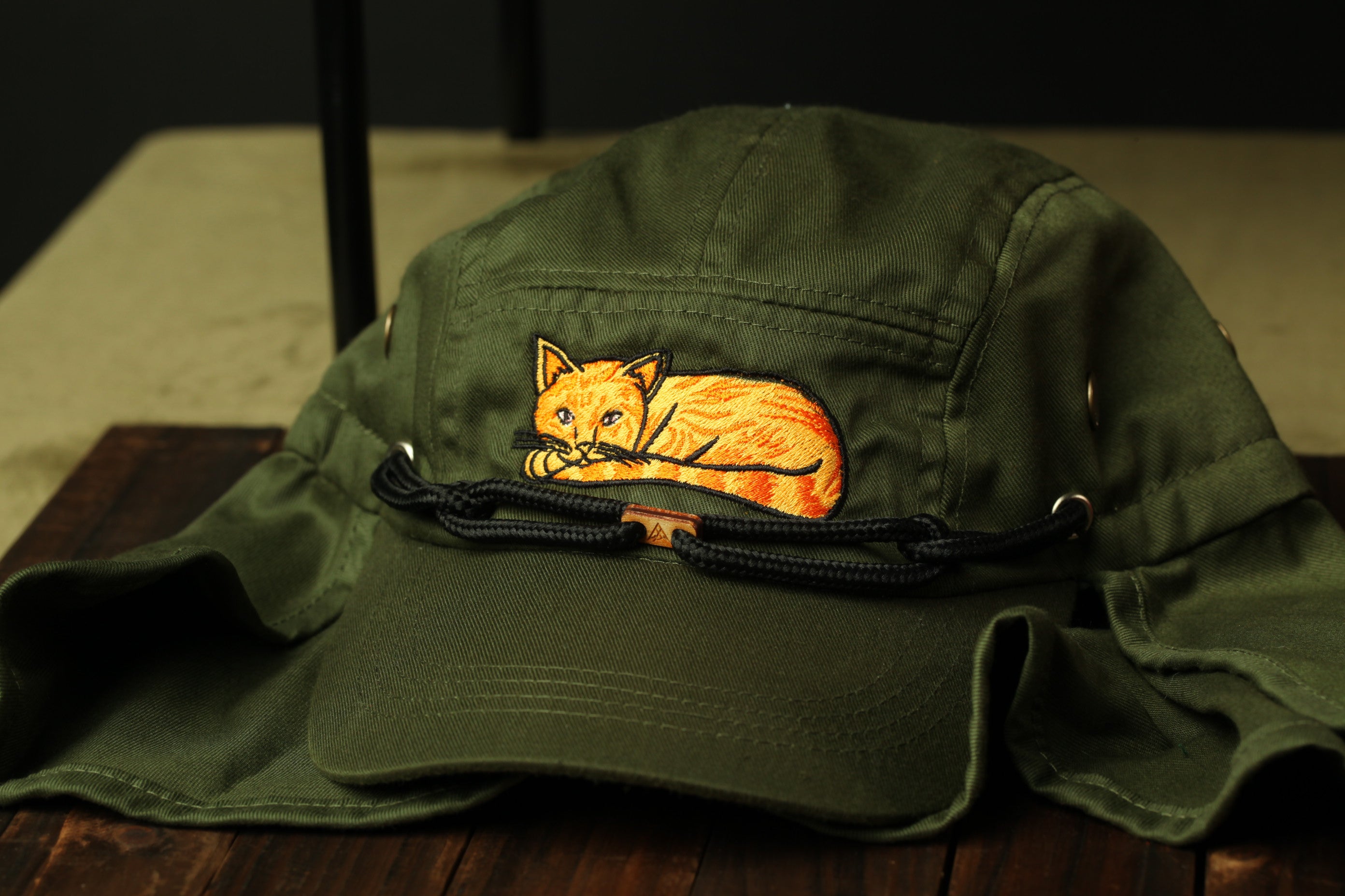 A green baseball cap with an embroidered image of a cat on the front.