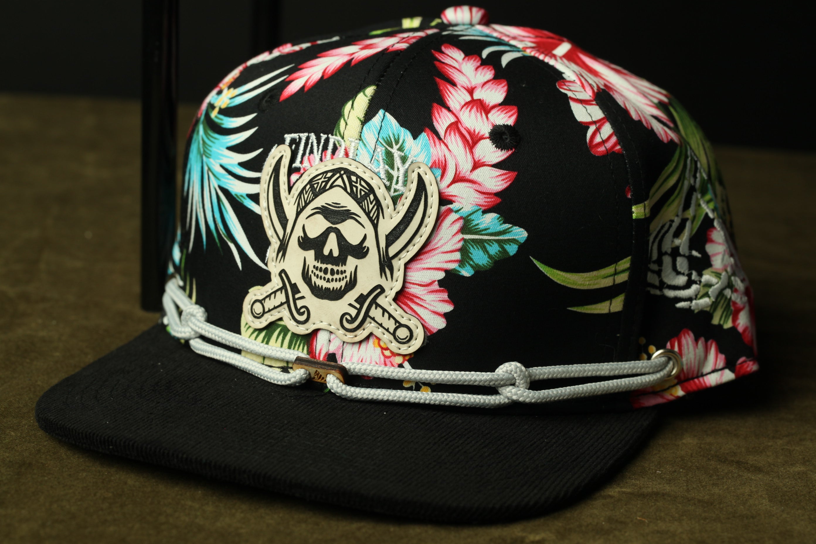 A colorful floral-patterned baseball cap with a skull and crossbones design on the front.