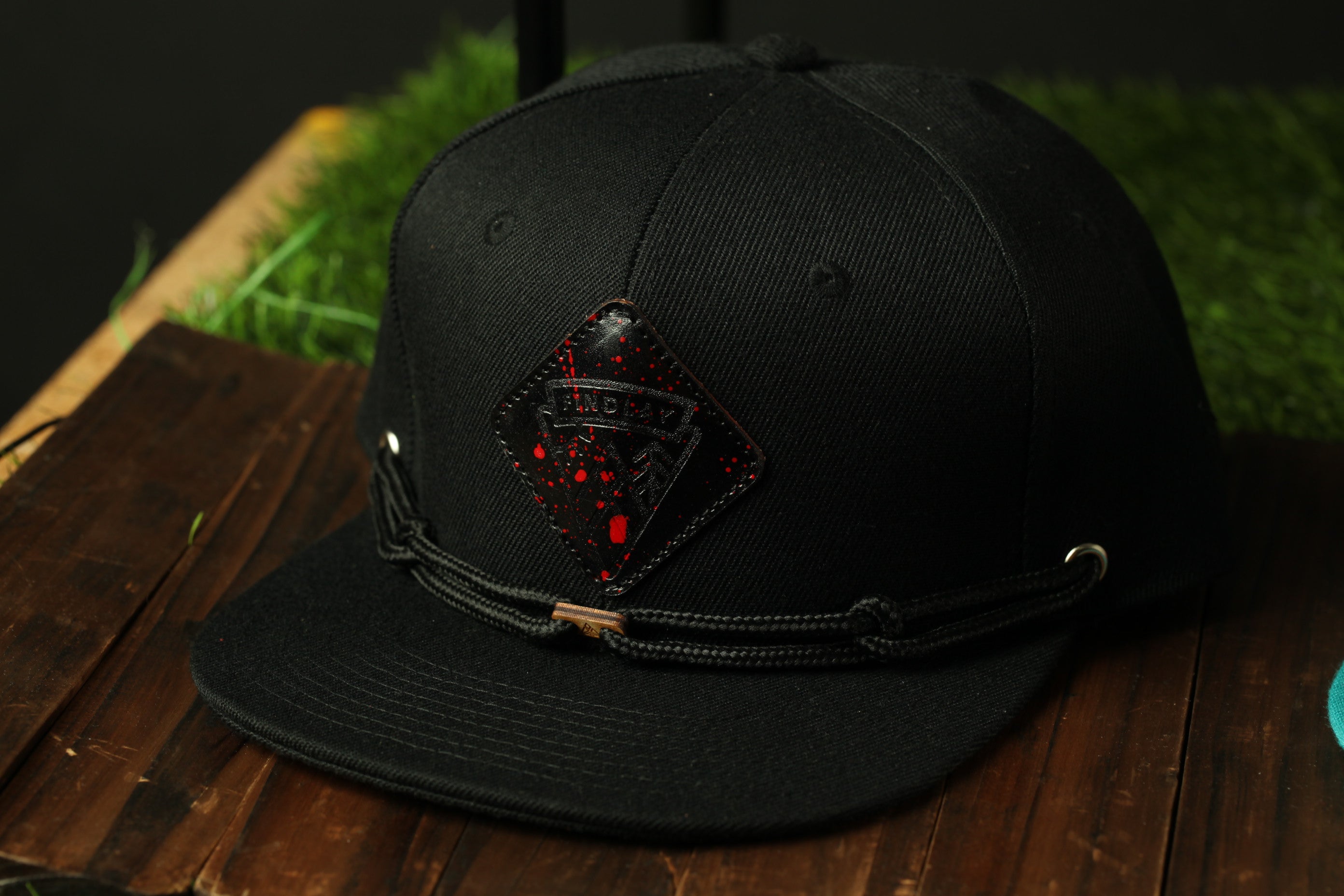 A black baseball cap with a red and black logo on the front, resting on a wooden surface.