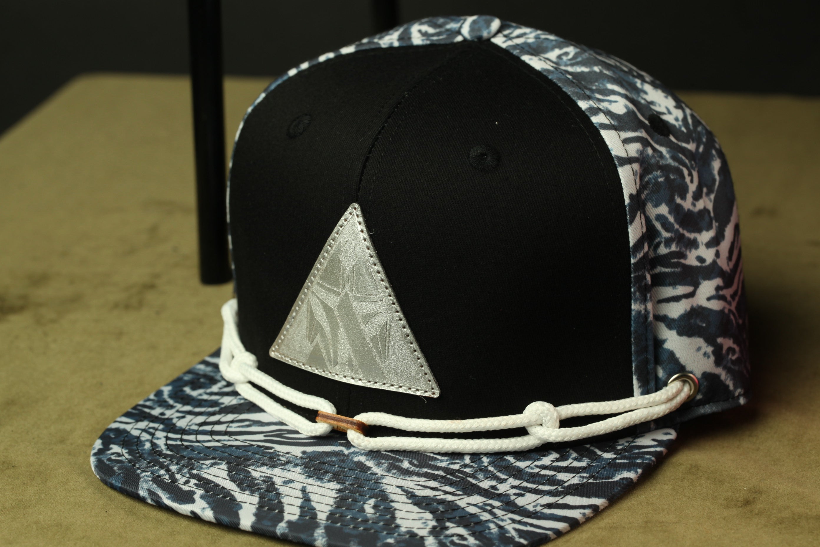 A black and white patterned baseball cap with a triangular patch on the front.