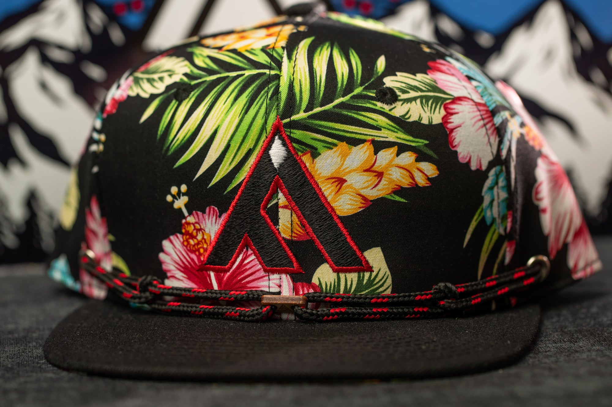 A colorful floral print baseball cap with a black brim and a red "A" logo on the front.