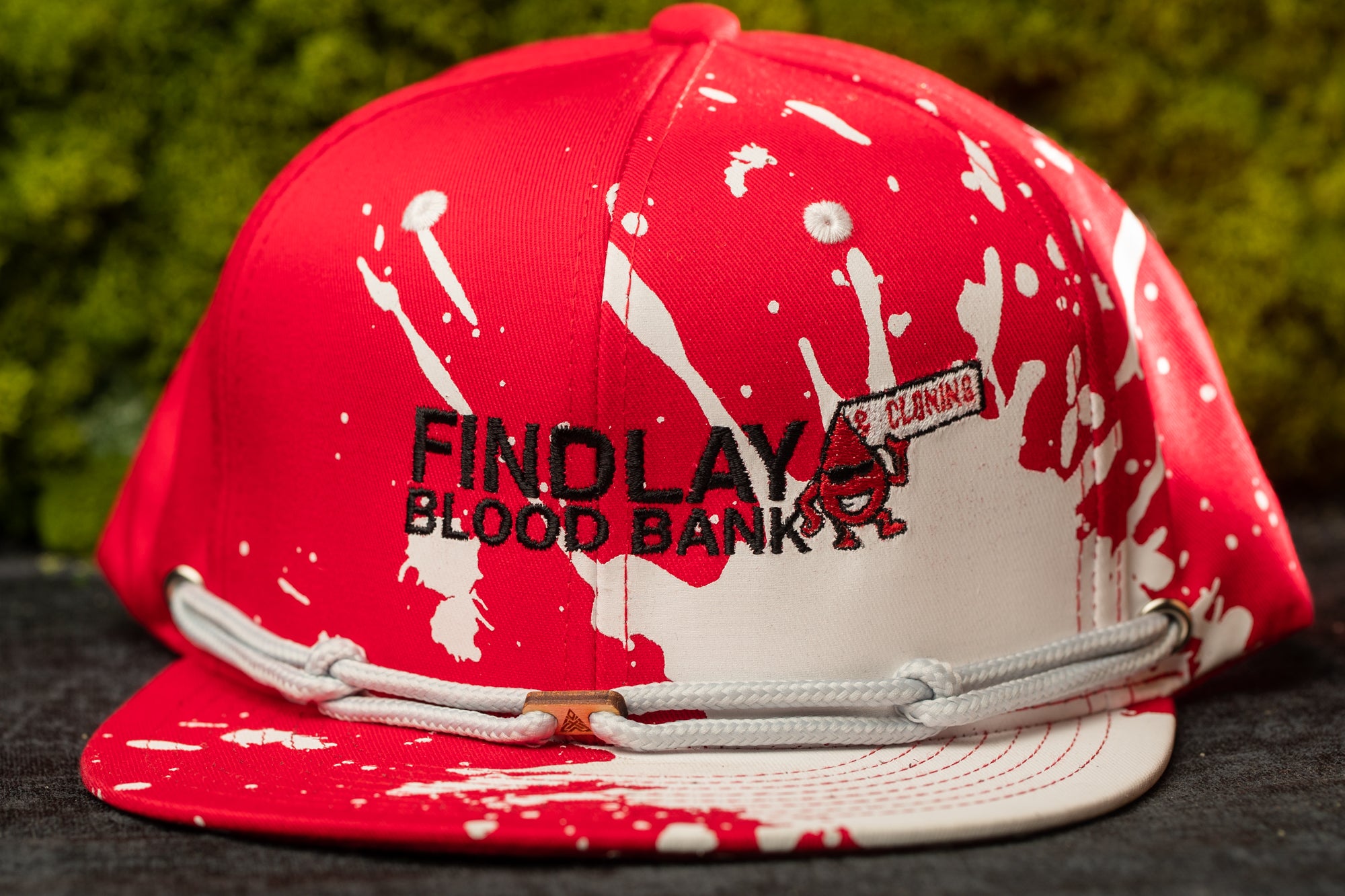 A red baseball cap with white splatters and the text "FIND LAY" printed on it.