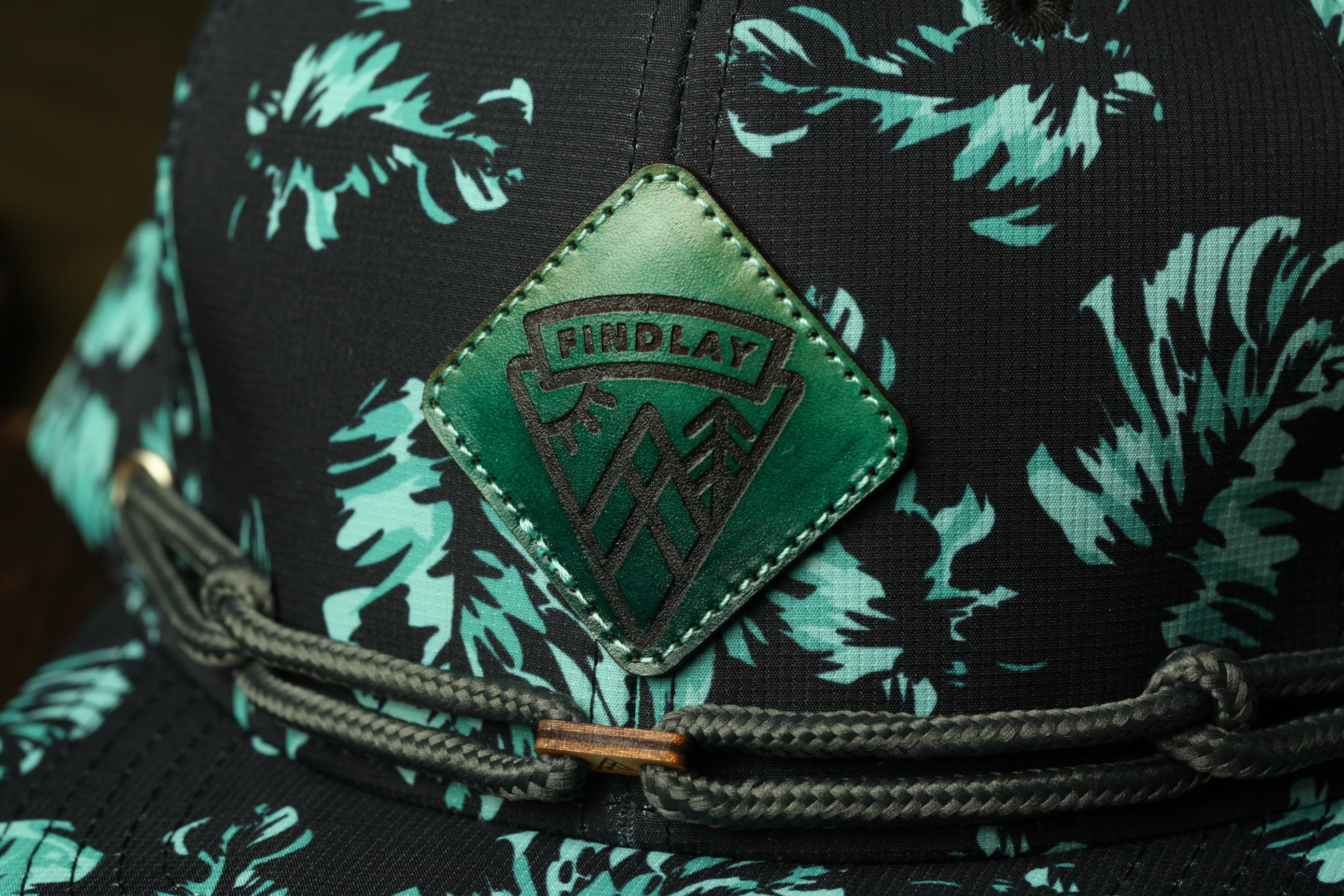 A close-up view of a black and green patterned hat with a green and black logo on the front.