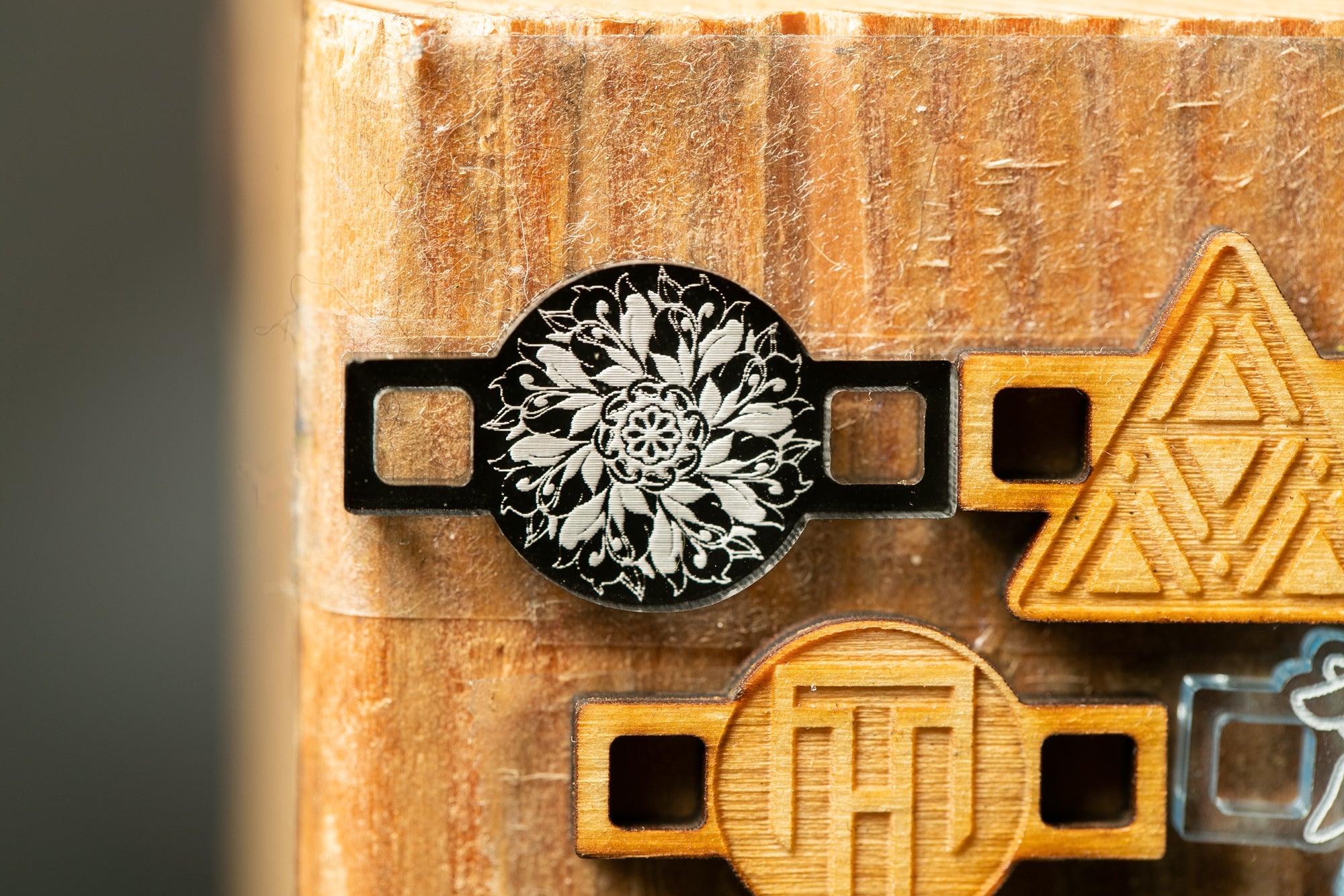 a close-up view of a wooden surface with various engraved shapes and designs, including a circular design with a floral pattern and a triangular shape.