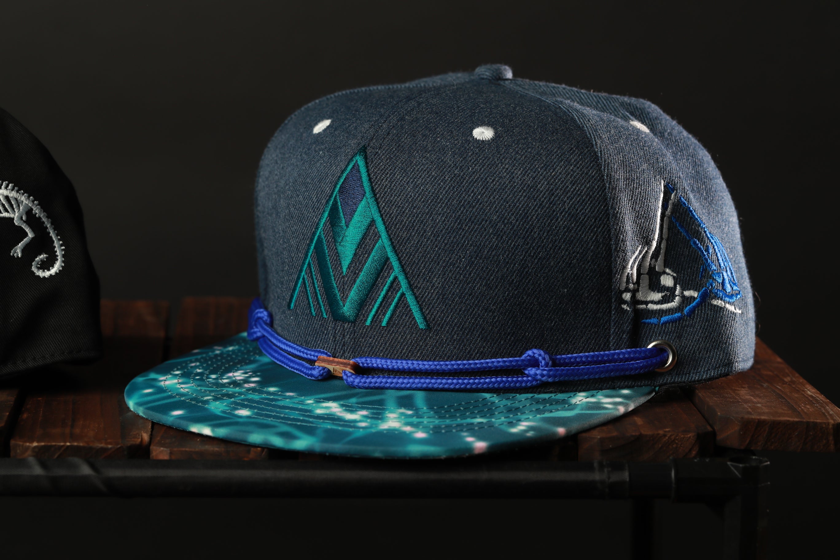 A navy blue baseball cap with a patterned brim and a blue band, displayed on a wooden surface.