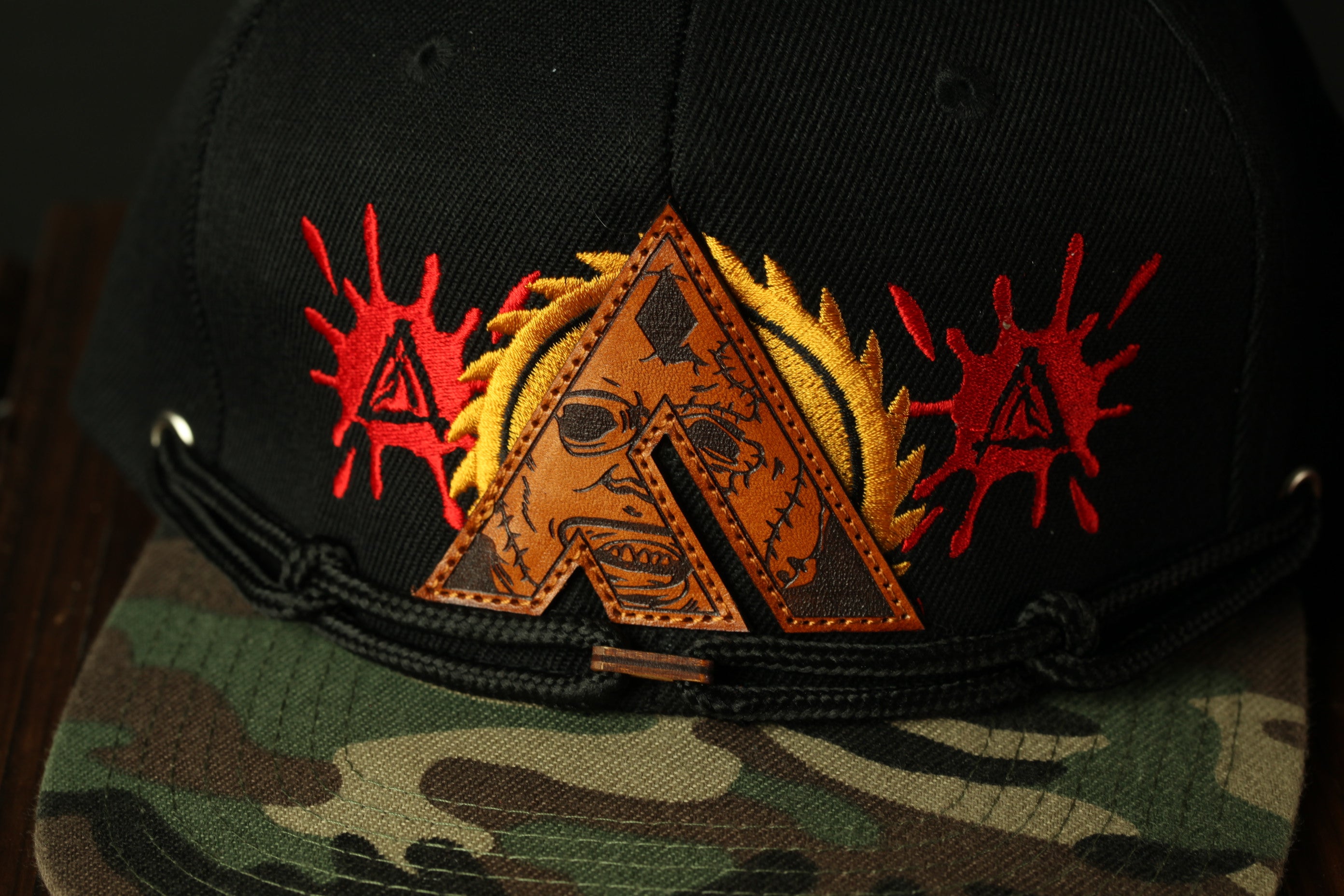 A close-up view of a black baseball cap with a unique embroidered design on the front.