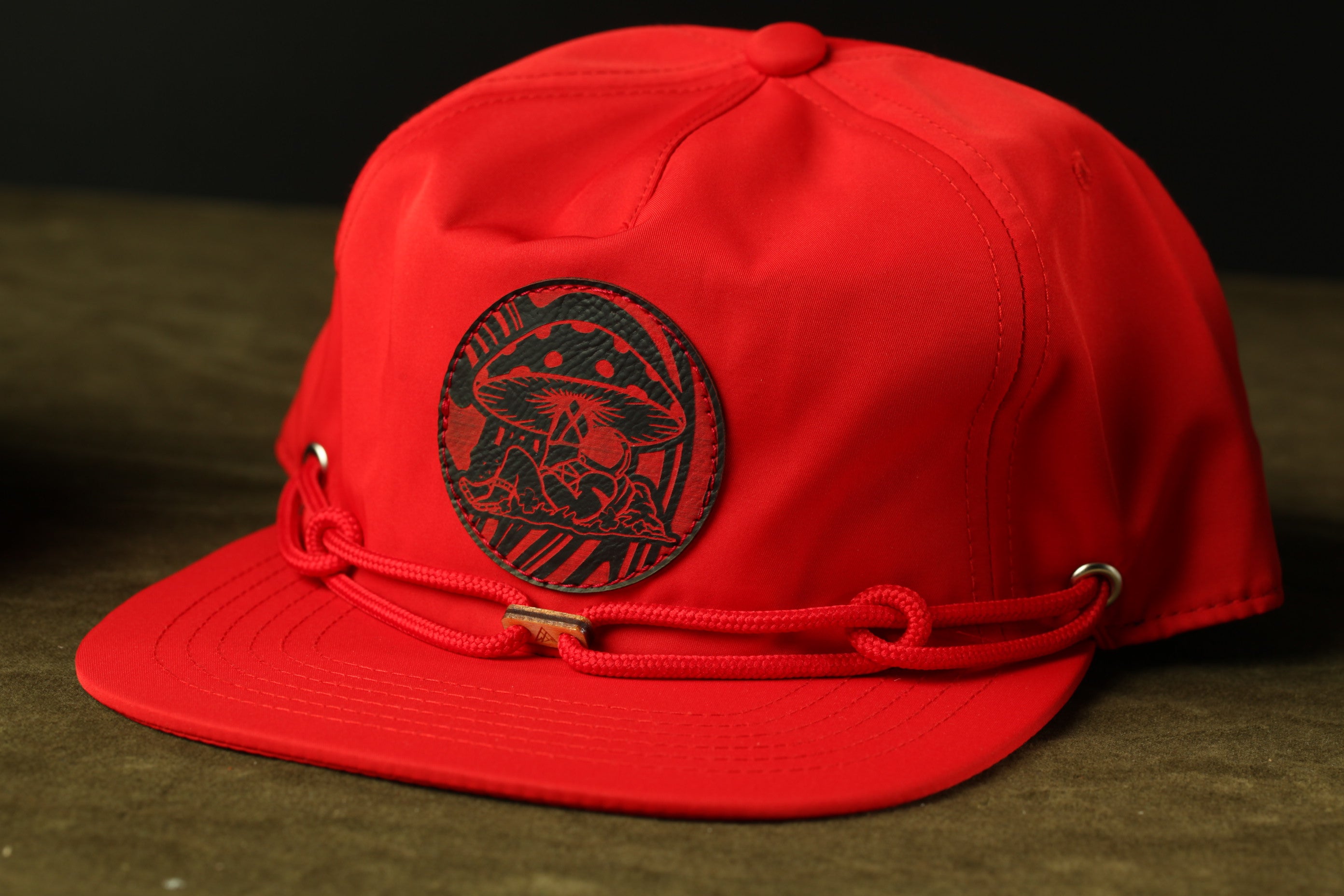 A red baseball cap with a black mushroom design on the front.