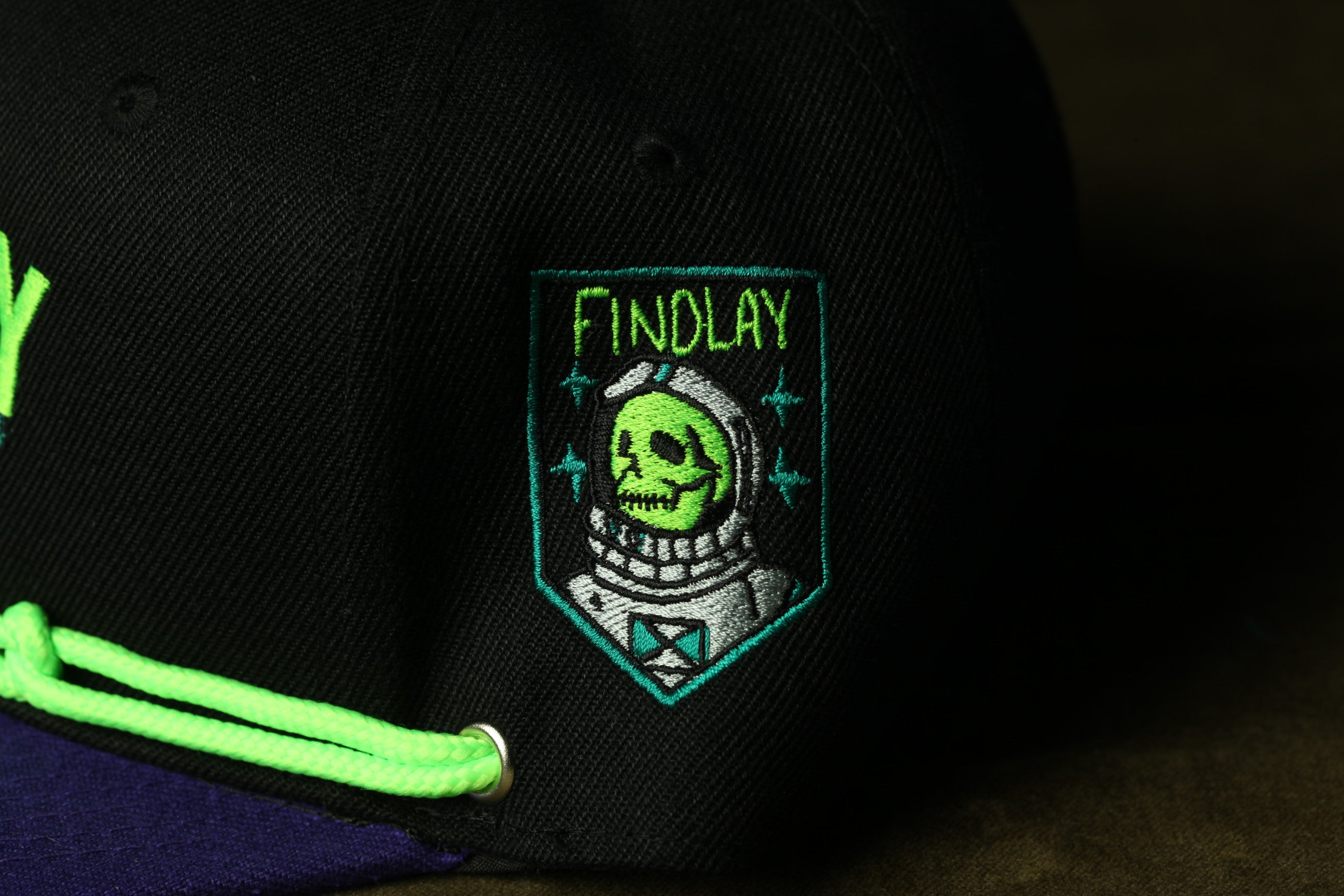 a close-up view of a black baseball cap with a green and white embroidered patch on the front.