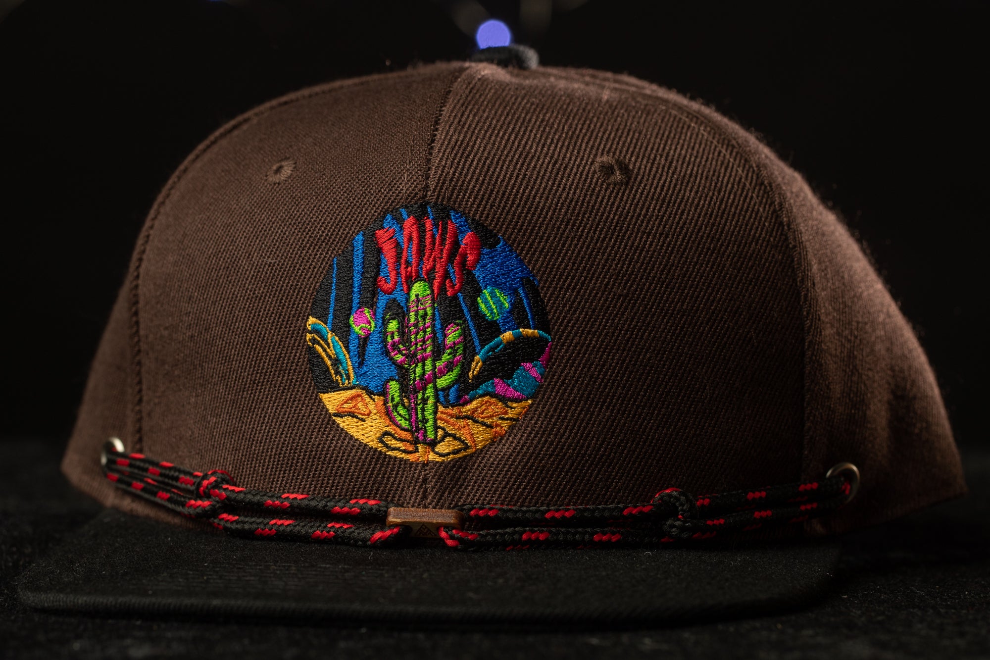 A brown baseball cap with a colorful embroidered design on the front.