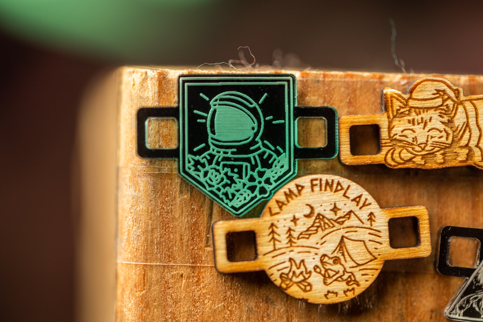 a wooden surface with several wooden badges or charms attached to it. The badges appear to be made of wood and are designed with various images and text.