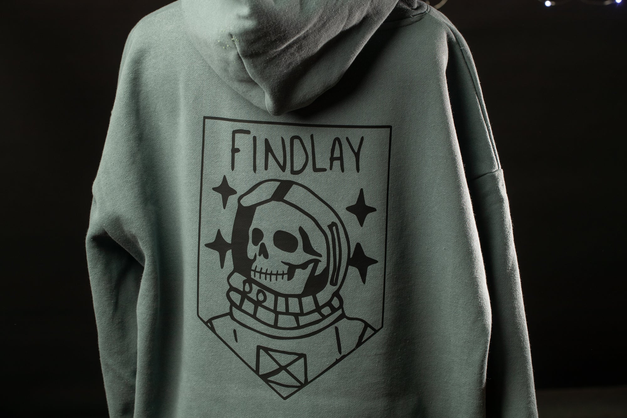 A person wearing a grey hooded sweatshirt with a graphic design on the back.