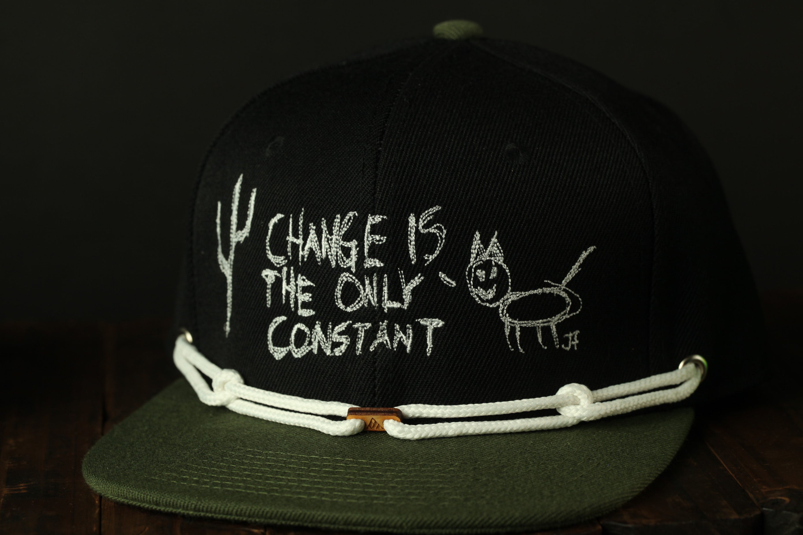 A black baseball cap with white text and a drawing on the front.