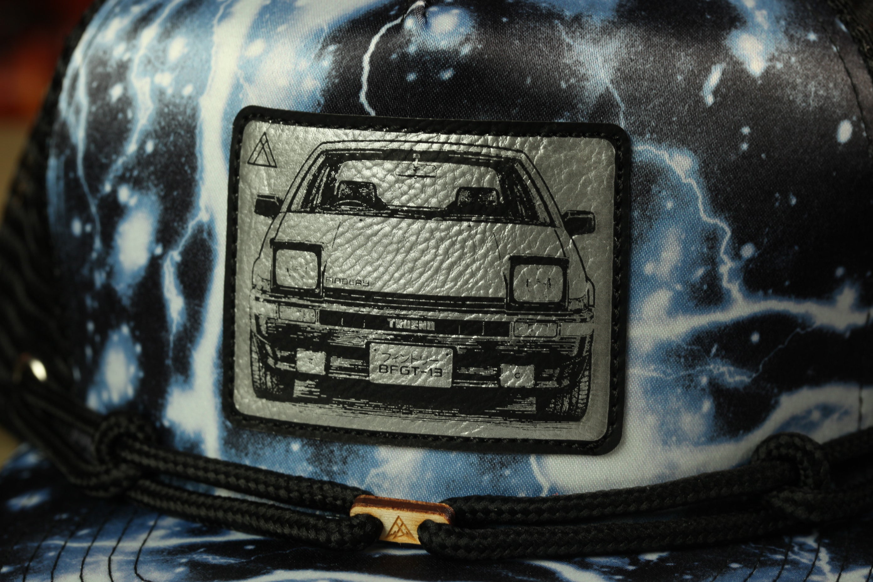 a close-up view of a car patch on a hat, with a black and white design depicting a car.