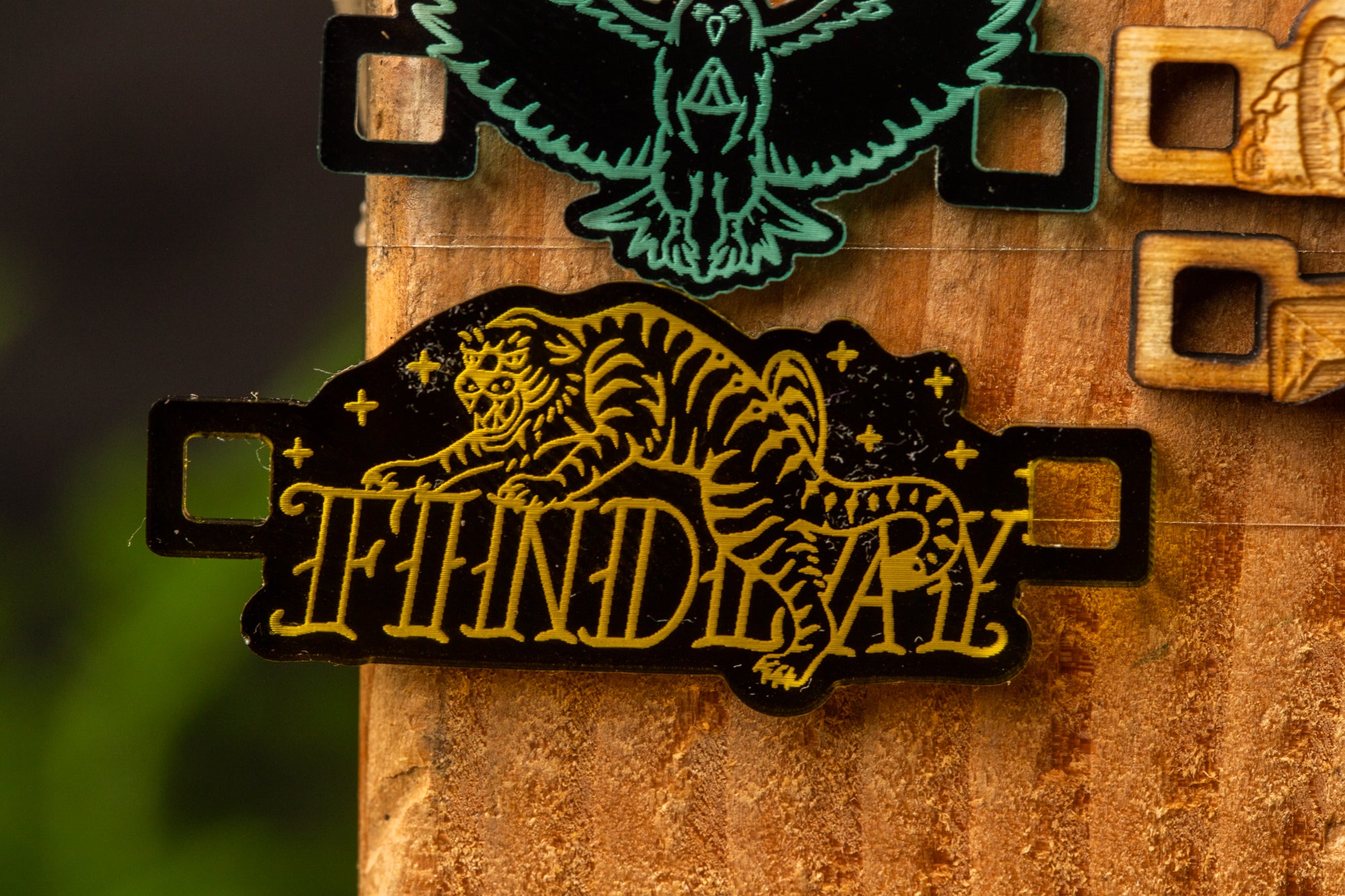 a close-up of a black and gold sticker or decal with a tiger design, attached to a wooden surface.