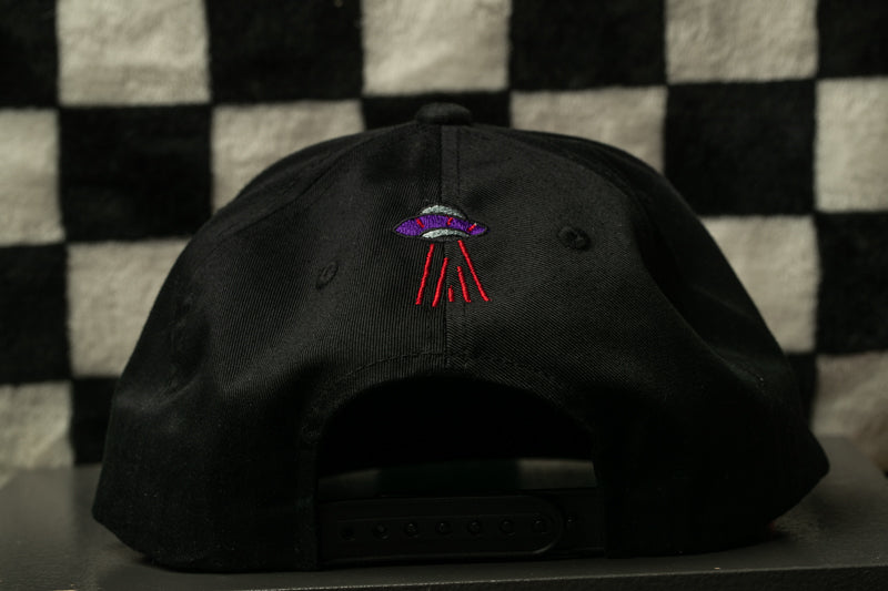 a black baseball cap with a purple and red embroidered alien design on the front.