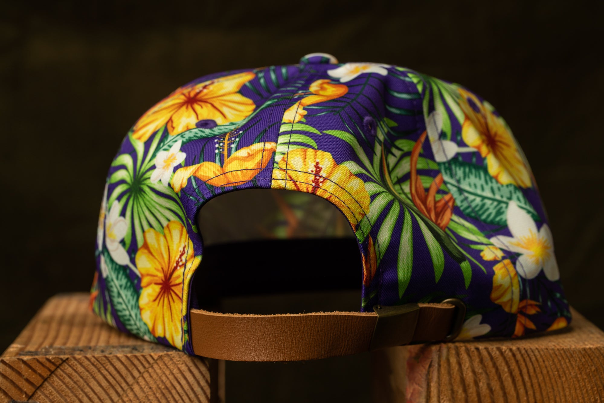 A colorful floral patterned baseball cap is displayed on a wooden surface.