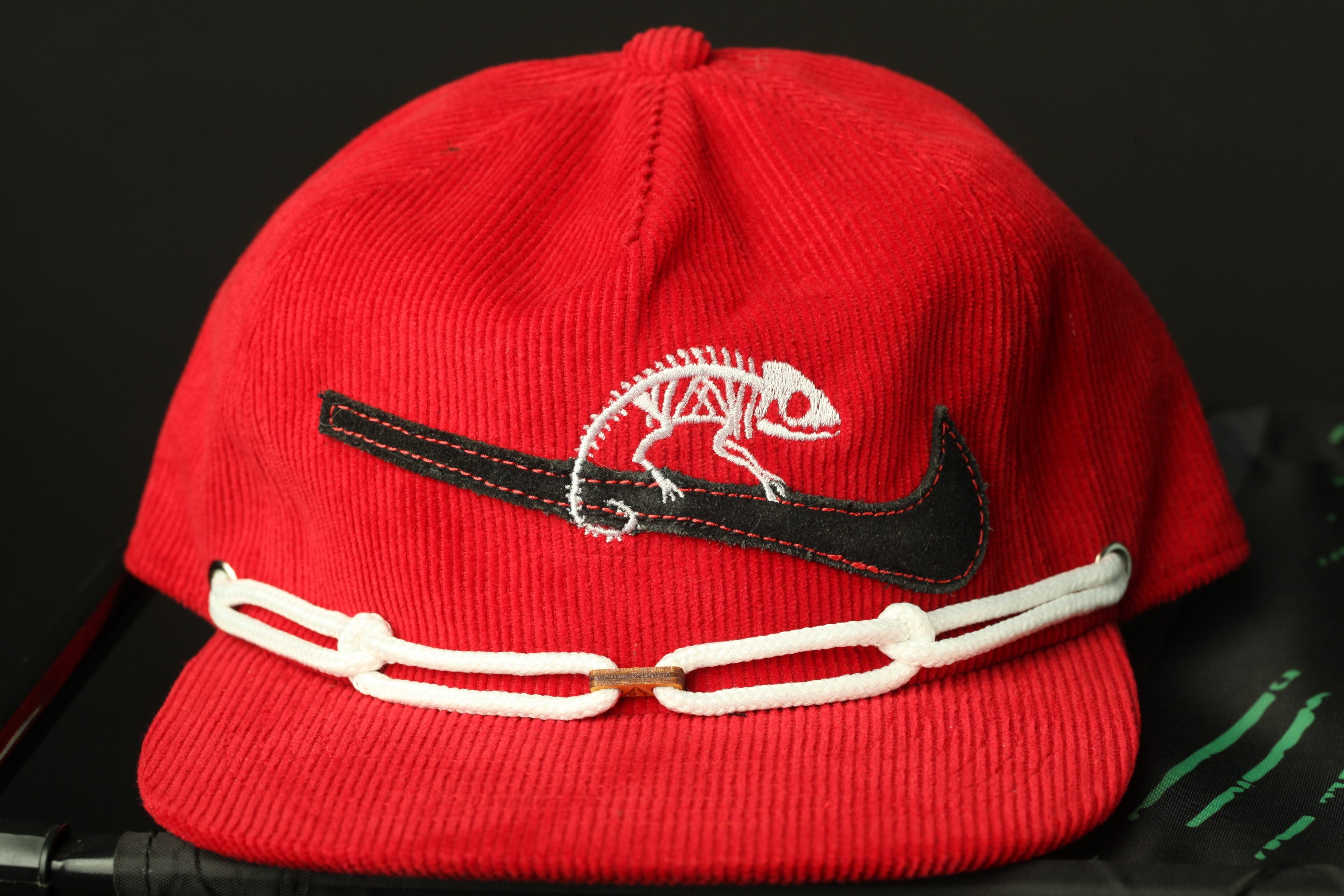 A red baseball cap with a black Nike swoosh and a white chain strap.