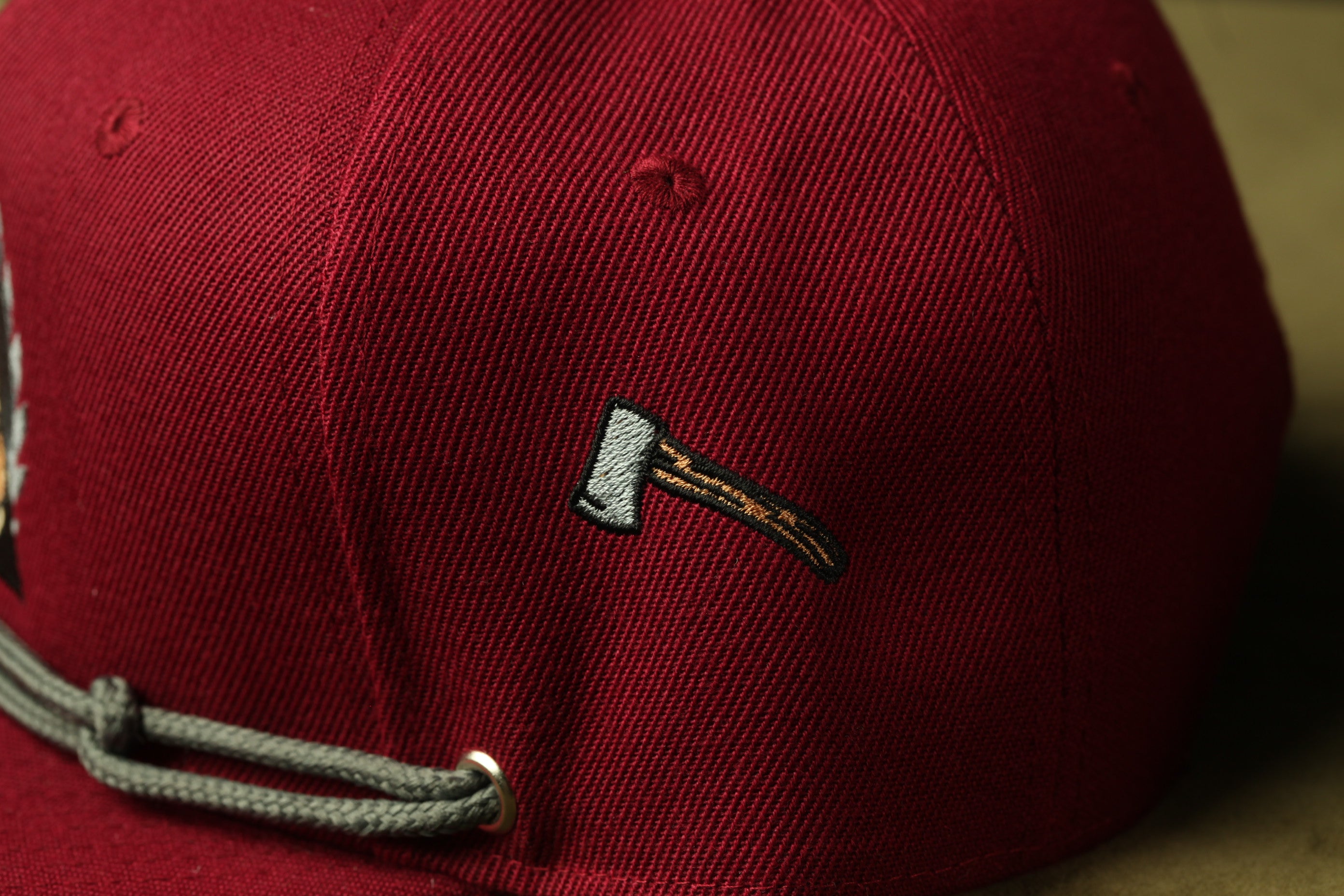 A close-up view of a red baseball cap with a small embroidered logo on the side.