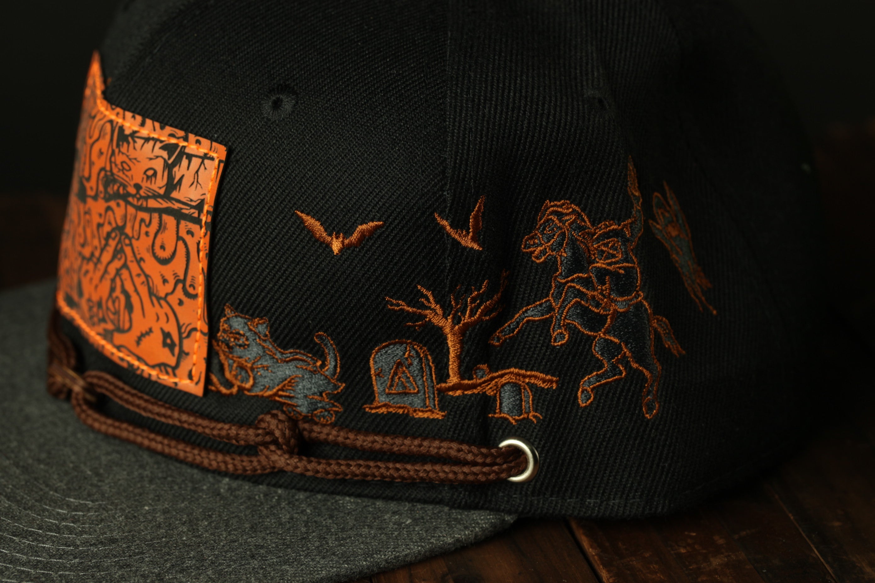a close-up view of a black baseball cap with various embroidered designs and patterns, including a bat, a horse, and a skull.