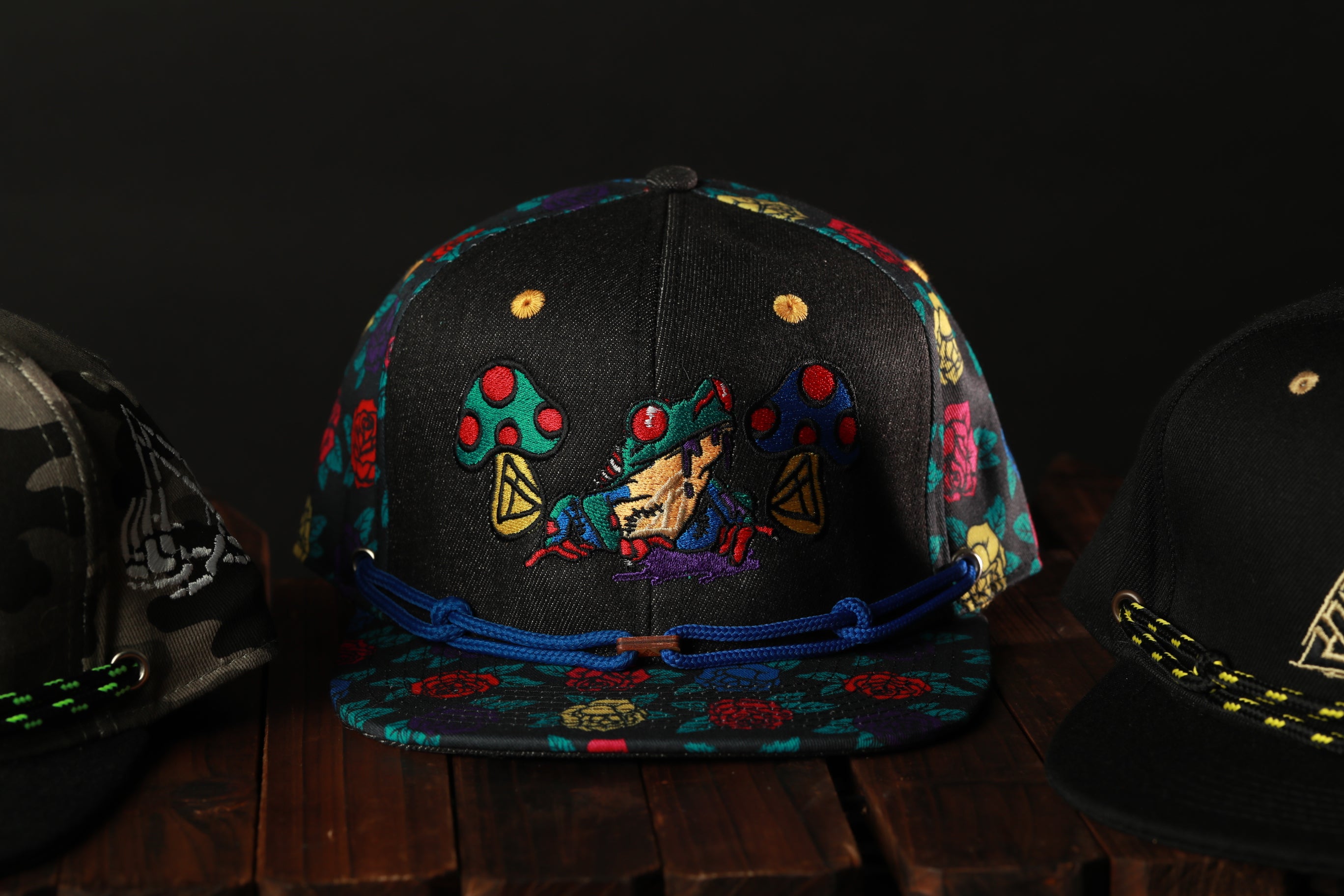 A colorful baseball cap with a cartoon character design, displayed on a wooden surface.