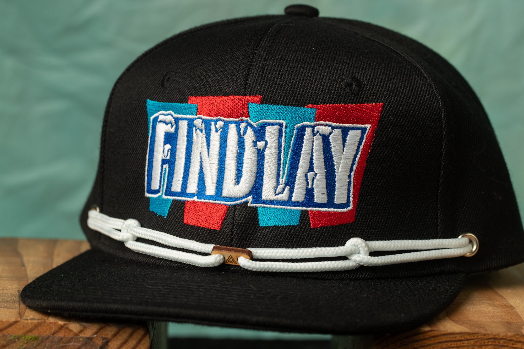 A black baseball cap with a white string and a colorful logo on the front.