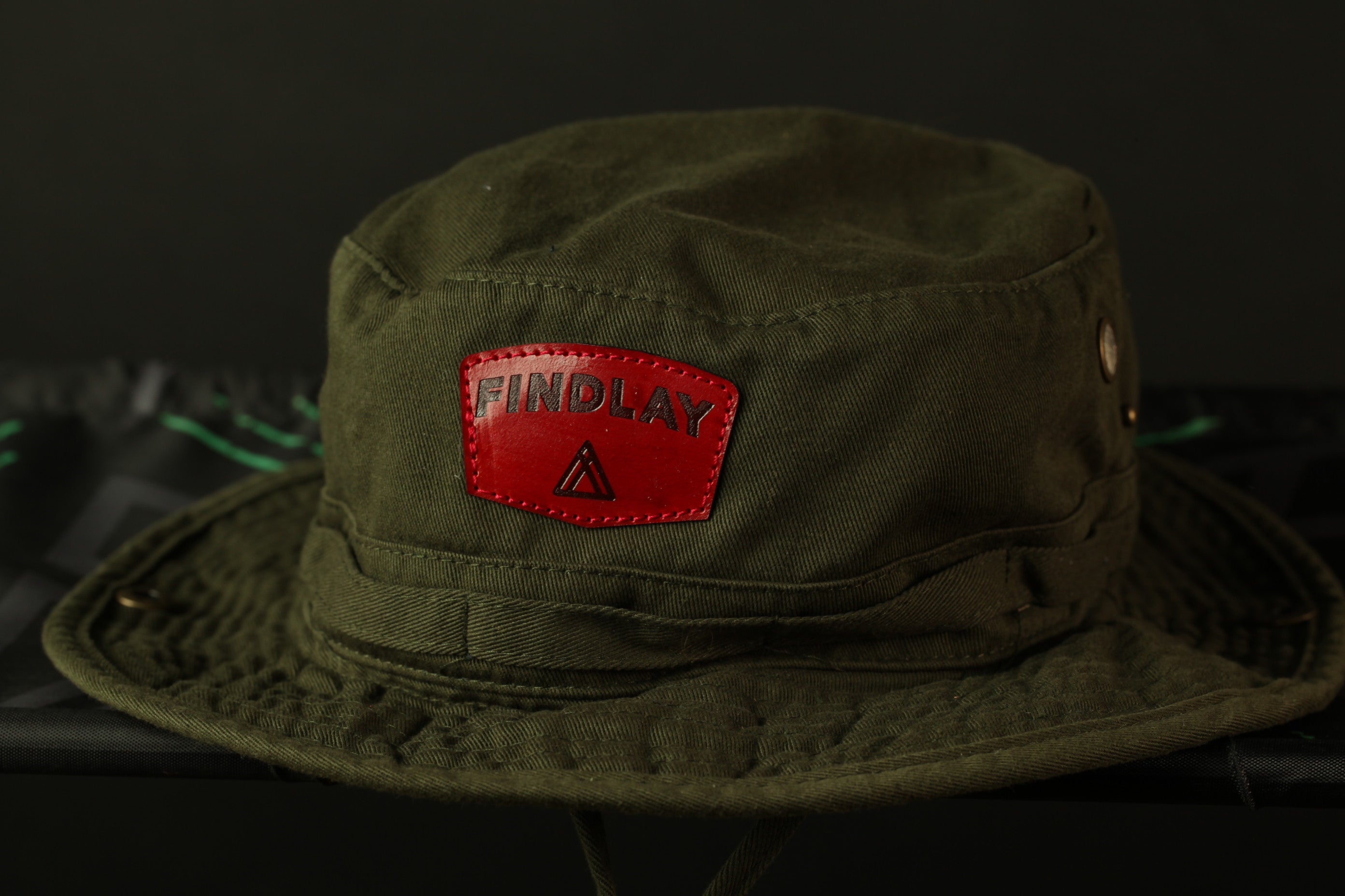 A green bucket hat with a red "FINDLAY" patch on the front.