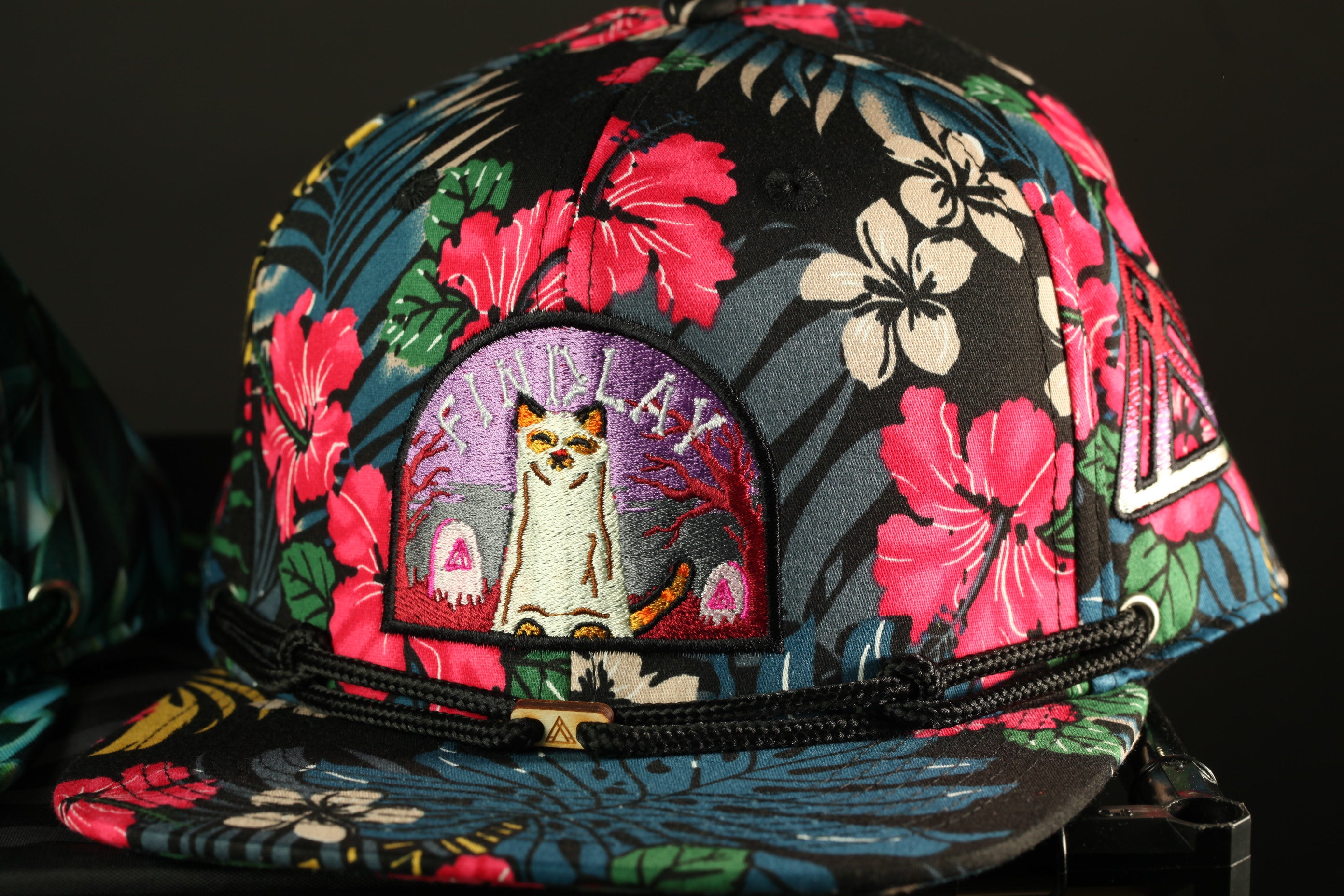 A colorful floral baseball cap with a cat embroidered on the front.