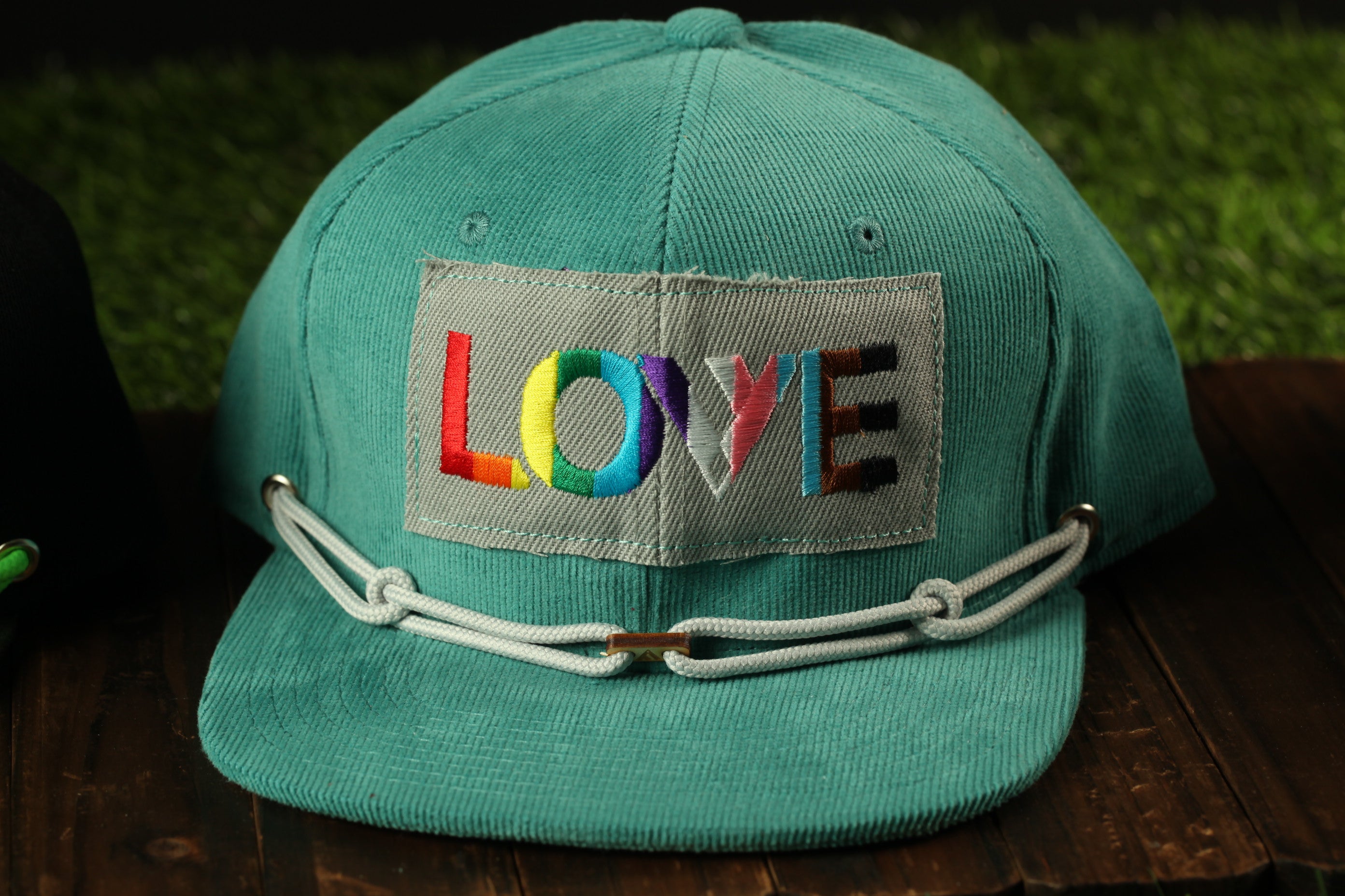 A turquoise baseball cap with a patch that says "LOVE" in colorful letters.