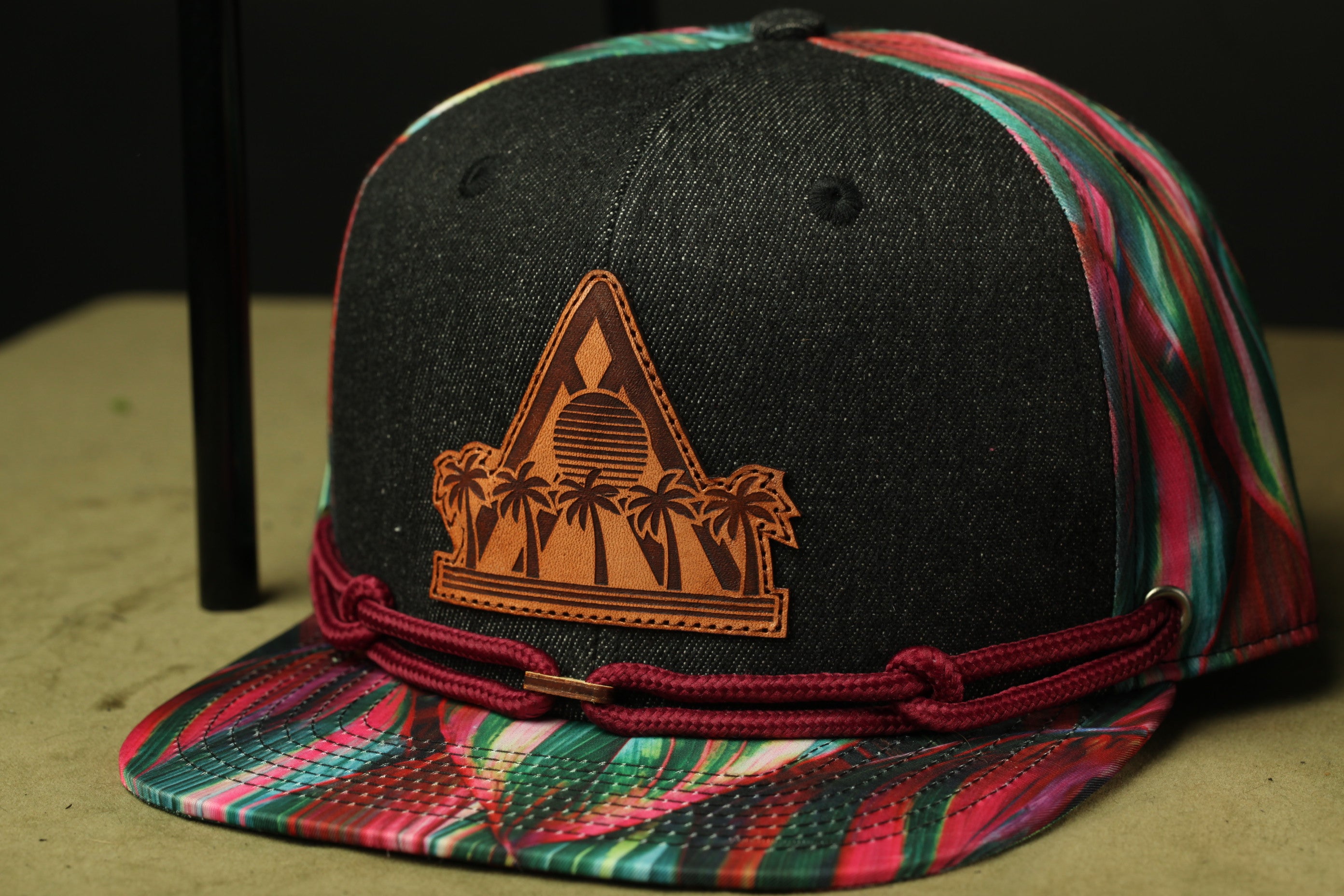 A colorful baseball cap with a leather patch featuring palm trees on it.
