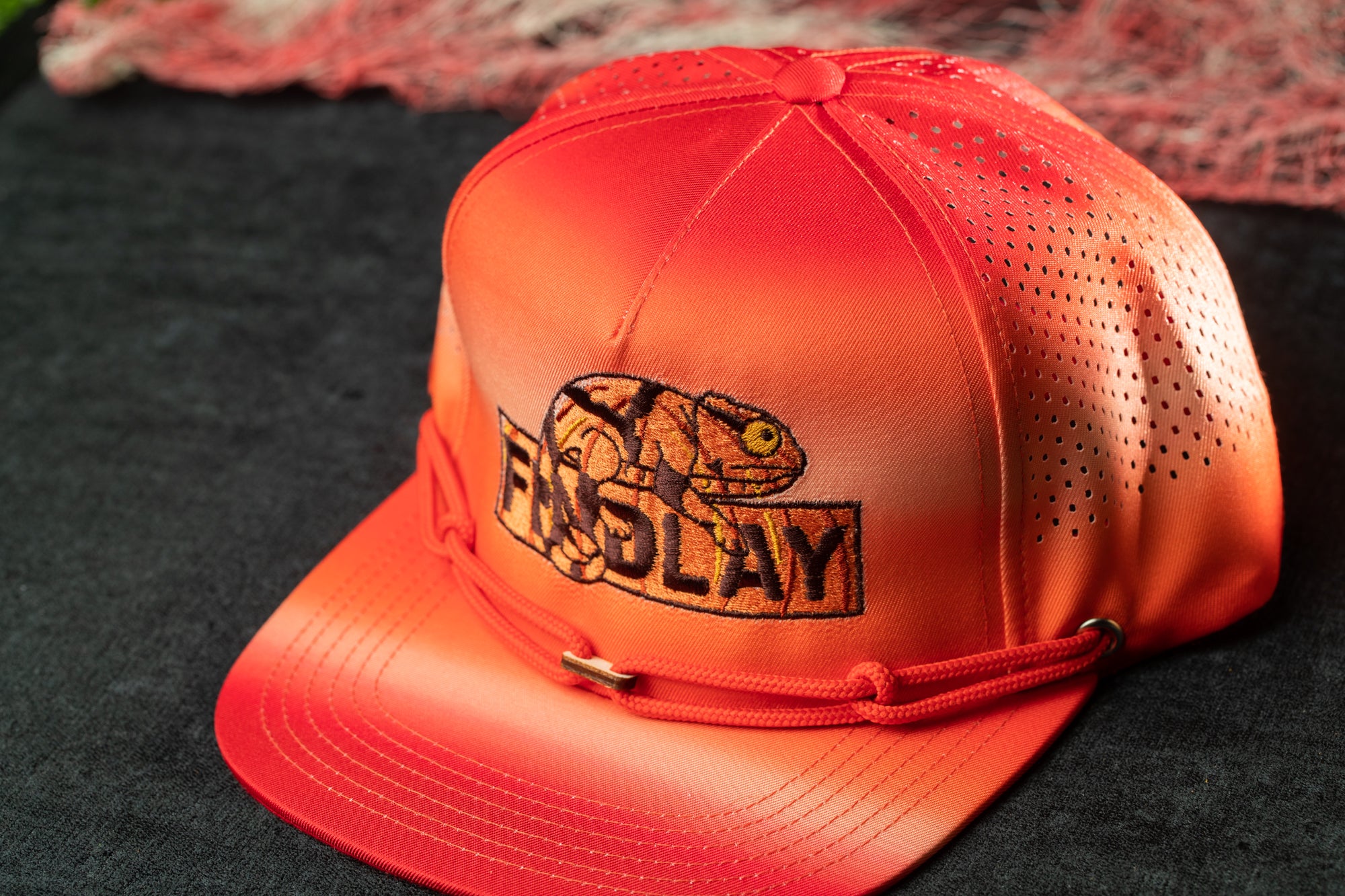 An orange baseball cap with a printed design on the front.
