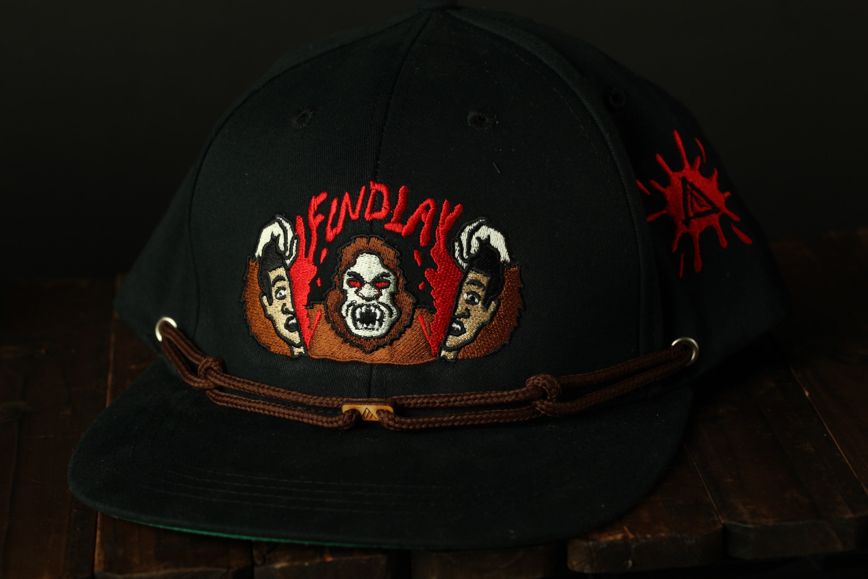 A black baseball cap with a red and white embroidered design featuring a skull and crossbones symbol, along with the text "FUND LA" on the front.