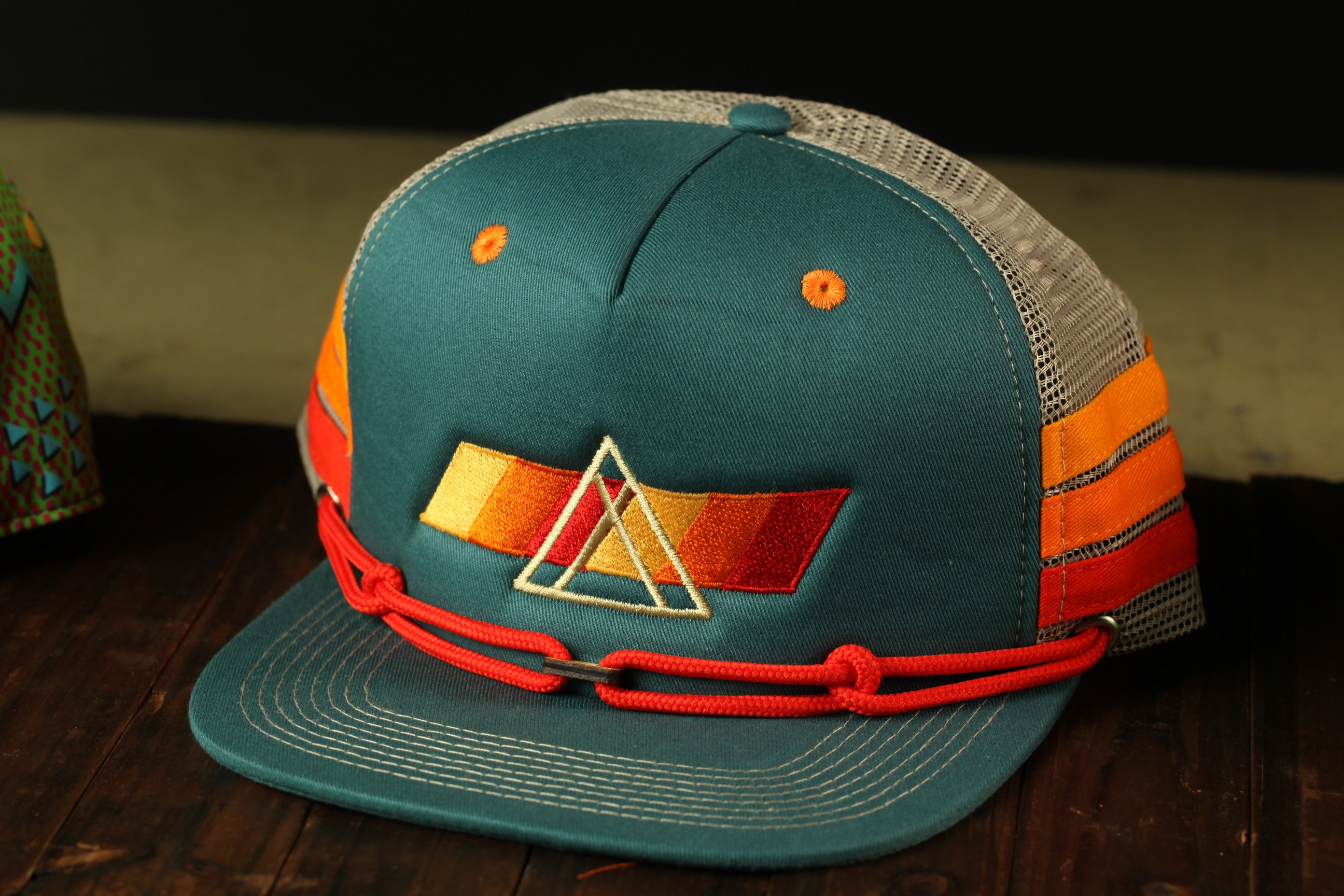 A green baseball cap with orange and red accents, featuring a triangular logo on the front.
