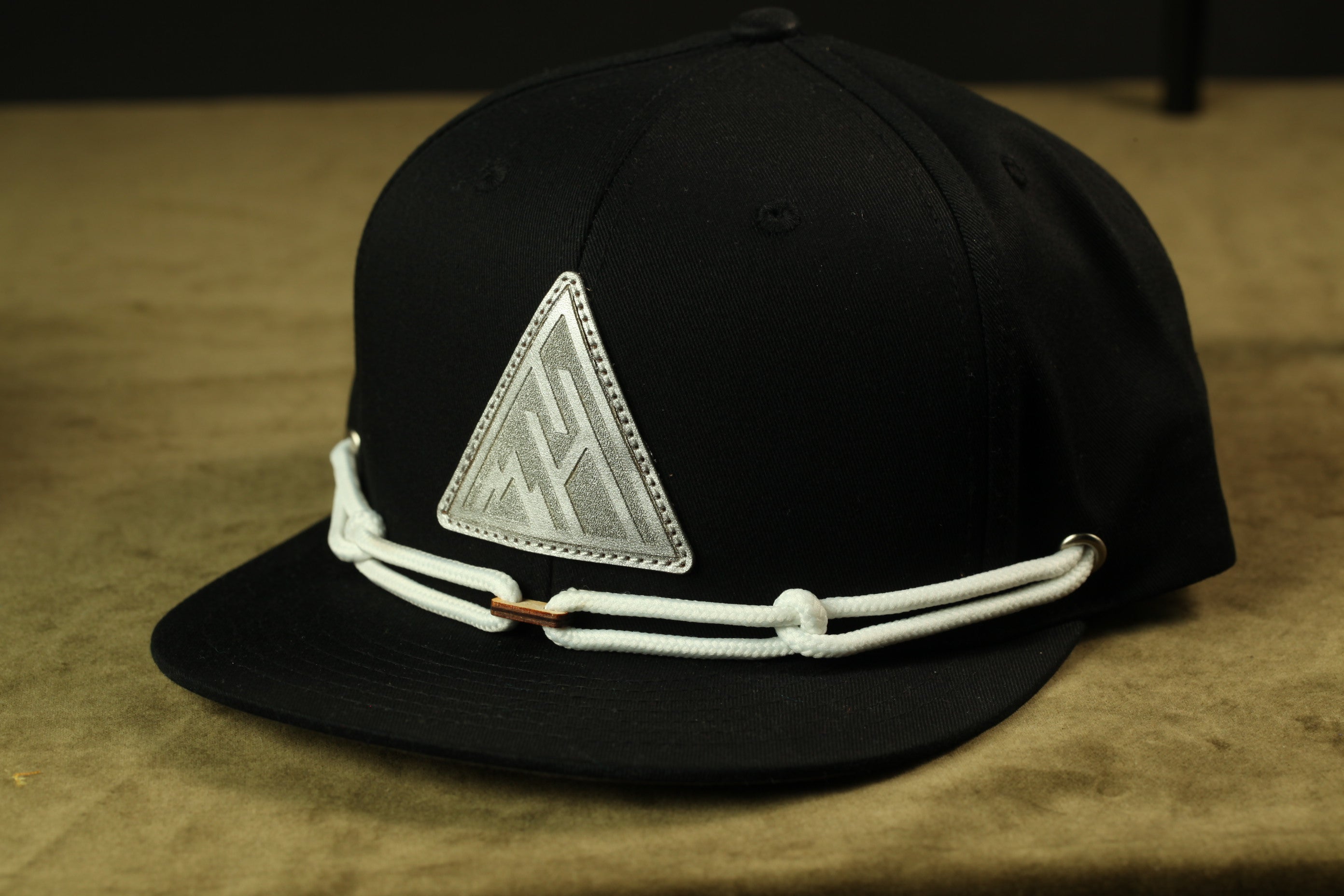 A black baseball cap with a white triangular patch on the front.