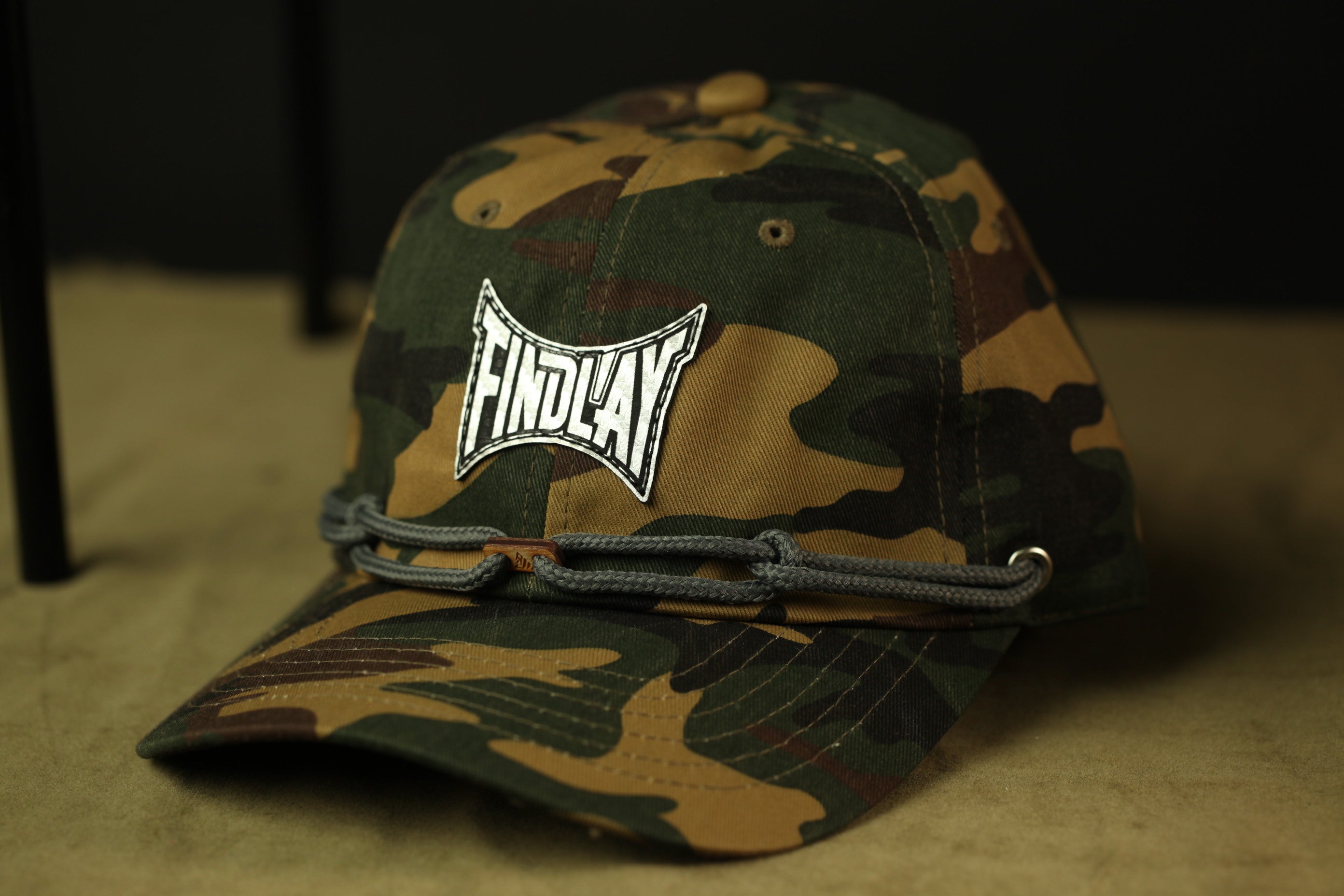 A camouflage baseball cap with the word "FINDLAY" printed on it.