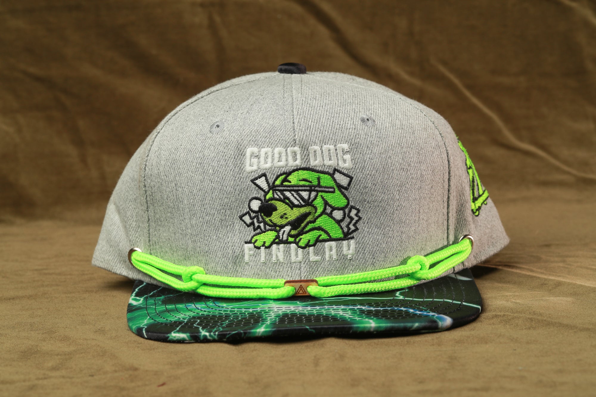 A gray baseball cap with a graphic of a dog wearing sunglasses and the text "GOOD DOG FIND LAY" printed on it.
