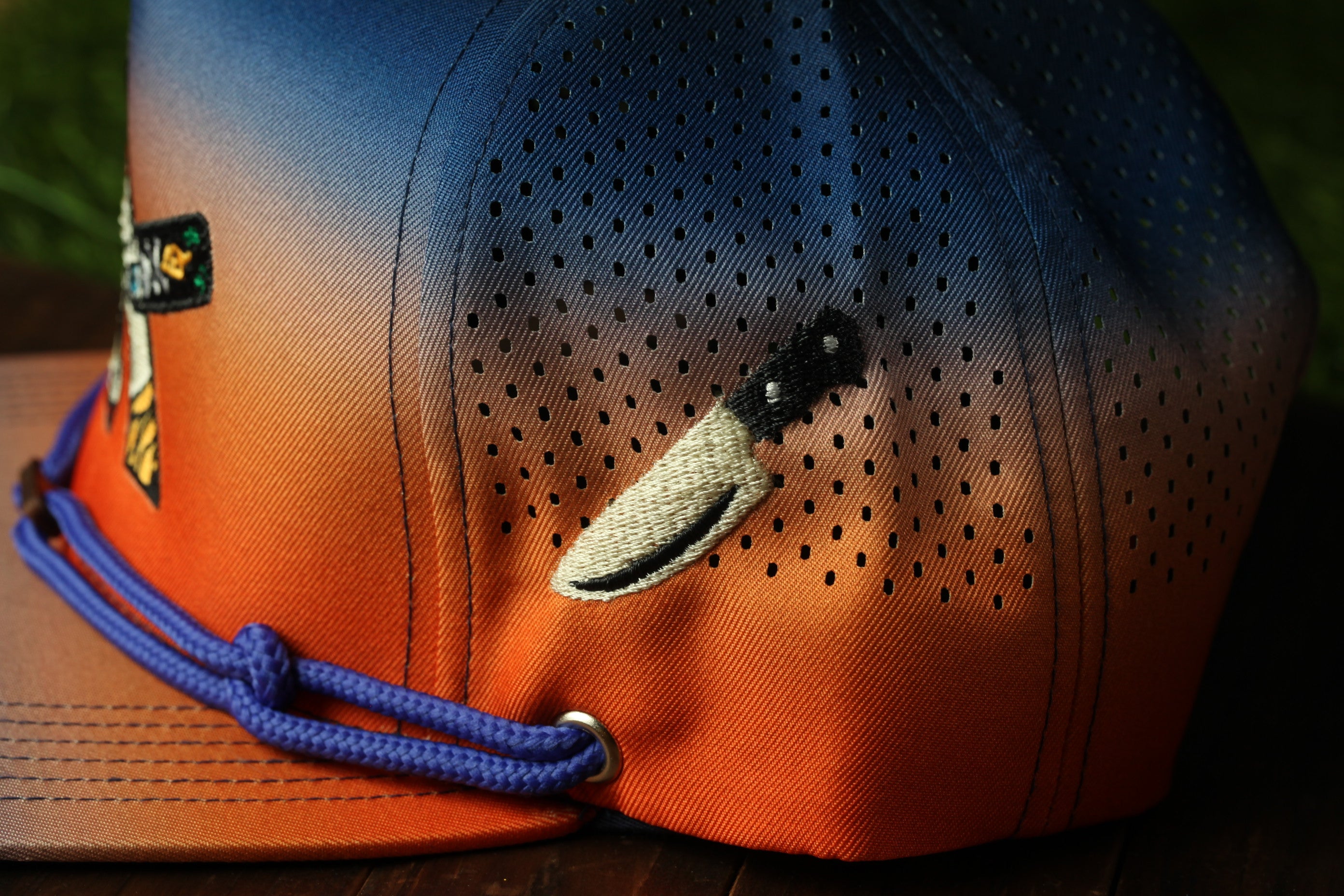 A close-up view of a colorful baseball cap with a knife embroidered on it.