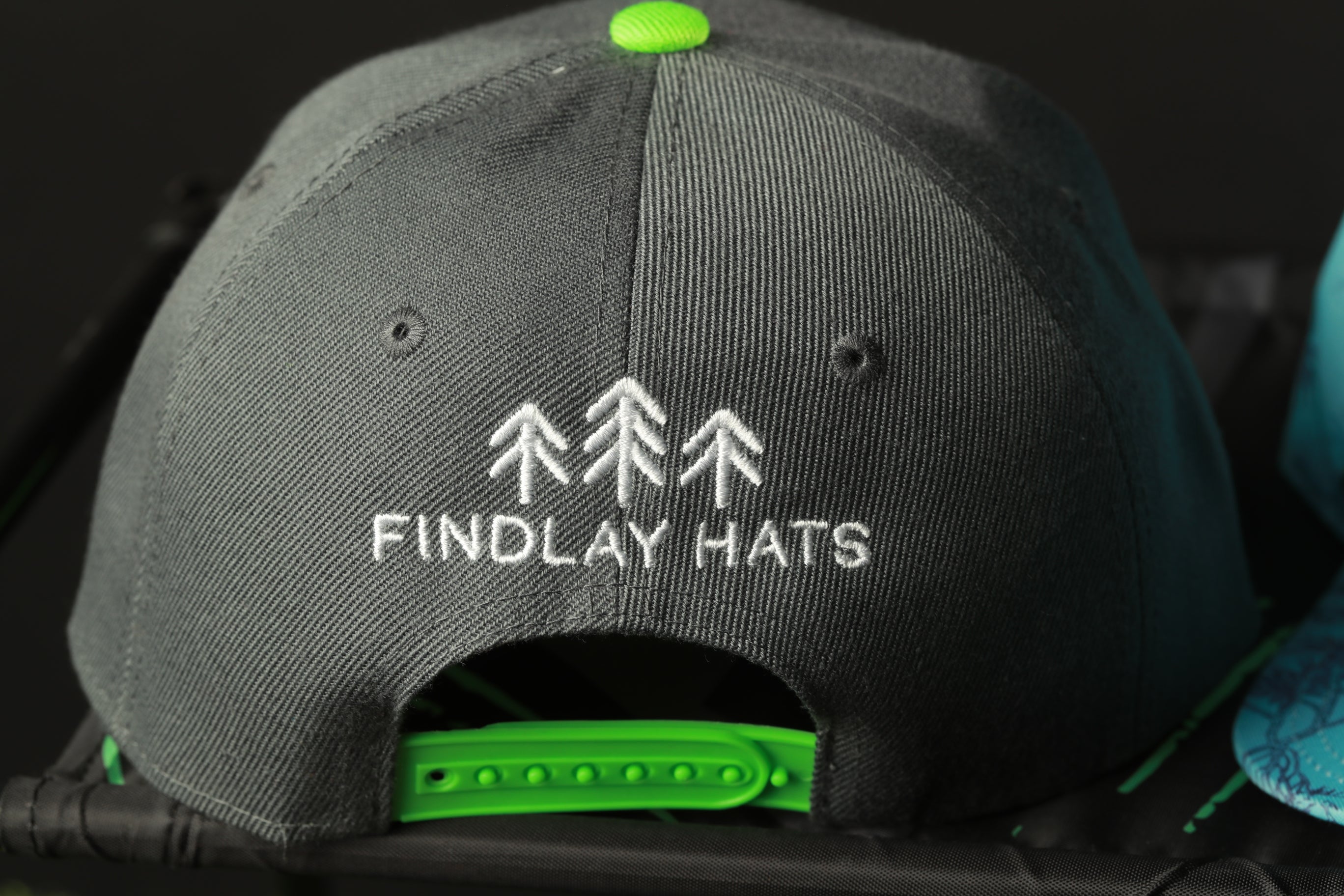 A black baseball cap with a green logo and text on it.