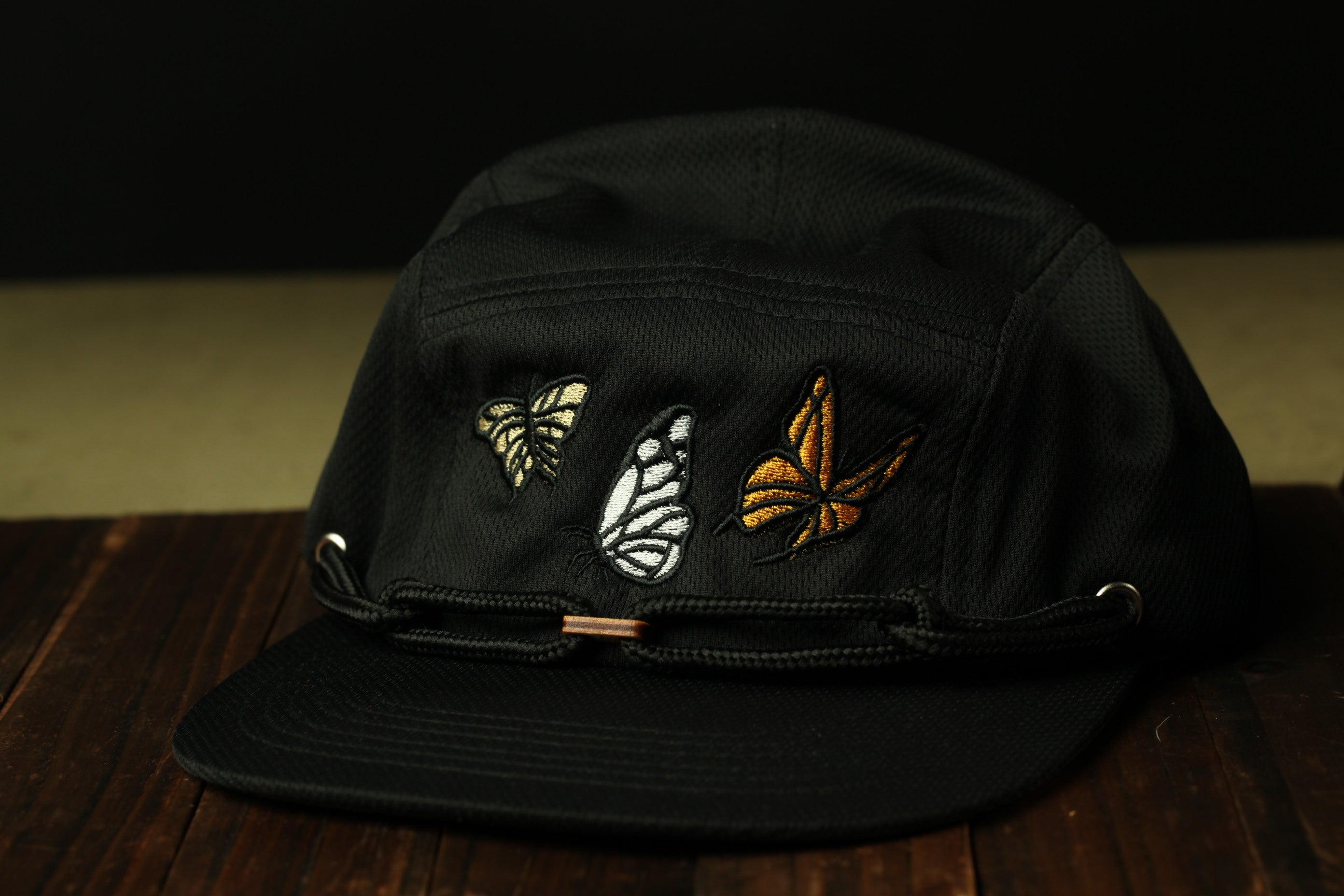 A black baseball cap with three embroidered butterflies on the front.