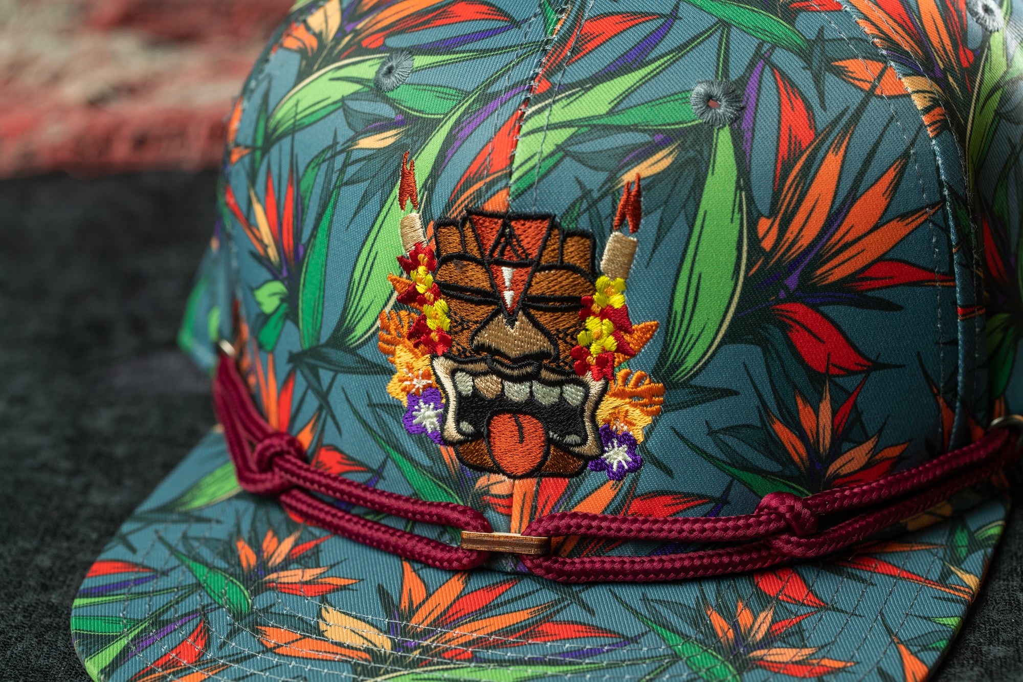 A colorful, patterned baseball cap with a tiki mask design on the front.
