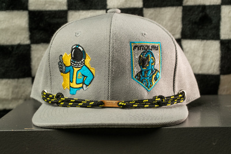 A gray baseball cap with two embroidered patches on the front, one depicting a person in a blue suit and the other showing a robot-like figure.